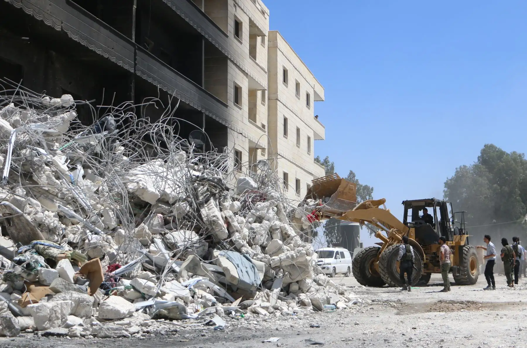 Un tractor limpia los escombros de los edificios destruidos el 13 de agosto de 2018 después de una explosión en un depósito de armas en una zona residencial en la ciudad de Sarmada en la norteña Siria de Idlib en la que decenas de personas murieron. / AFP