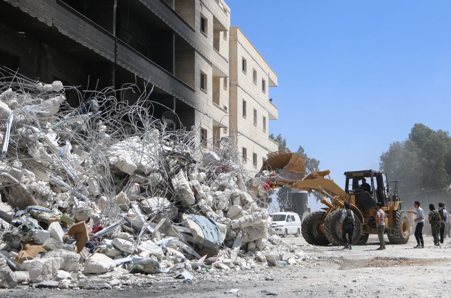 Un tractor limpia escombros de edificios destruidos tras explosión en un depósito de armas en Siria Foto: AFP