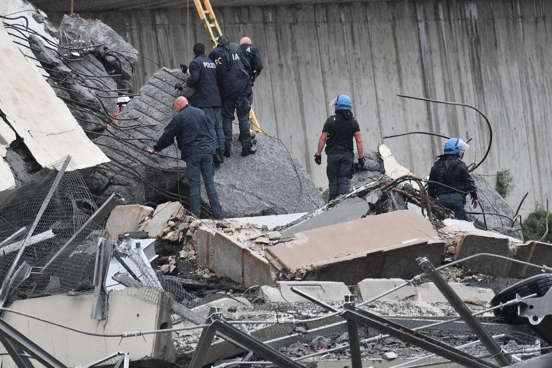Miembros de los servicios de emergencia buscan entre los escombros tras derrumbarse una sección del viaducto Morandi en Génova (Italia) hoy, 14 de agosto de 2018. EFE