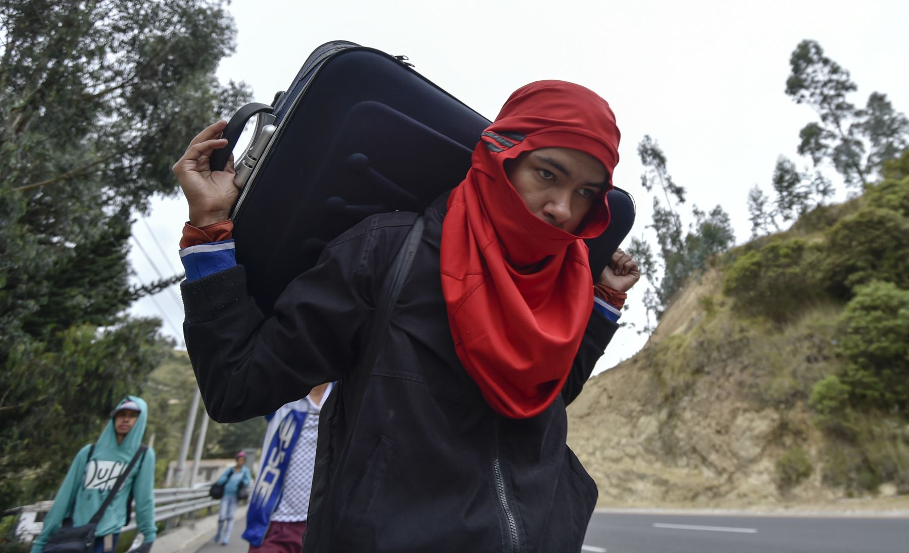 Un venezolano que se dirige a Perú lleva una maleta mientras camina por la carretera Panamericana en Tulcán, Ecuador, después de cruzar desde Colombia, el 21 de agosto de 2018. Foto: AFP