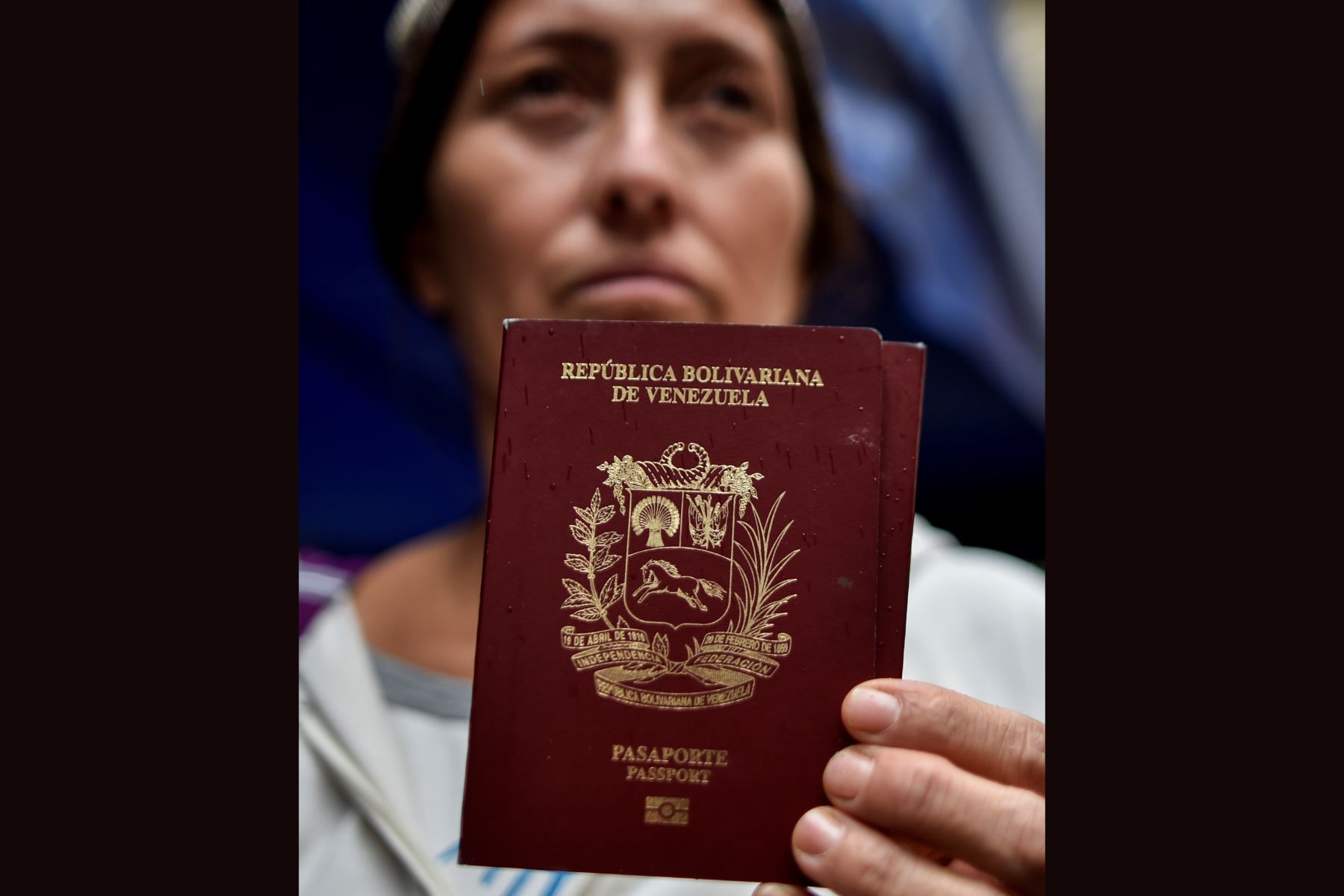 Una mujer venezolana muestra su pasaporte frente a la oficina de migración de Colombia a lo largo del puente internacional Rumichaca antes de cruzar de Ipiales en Colombia a Tulcán en Ecuador y Perú. Foto: AFP