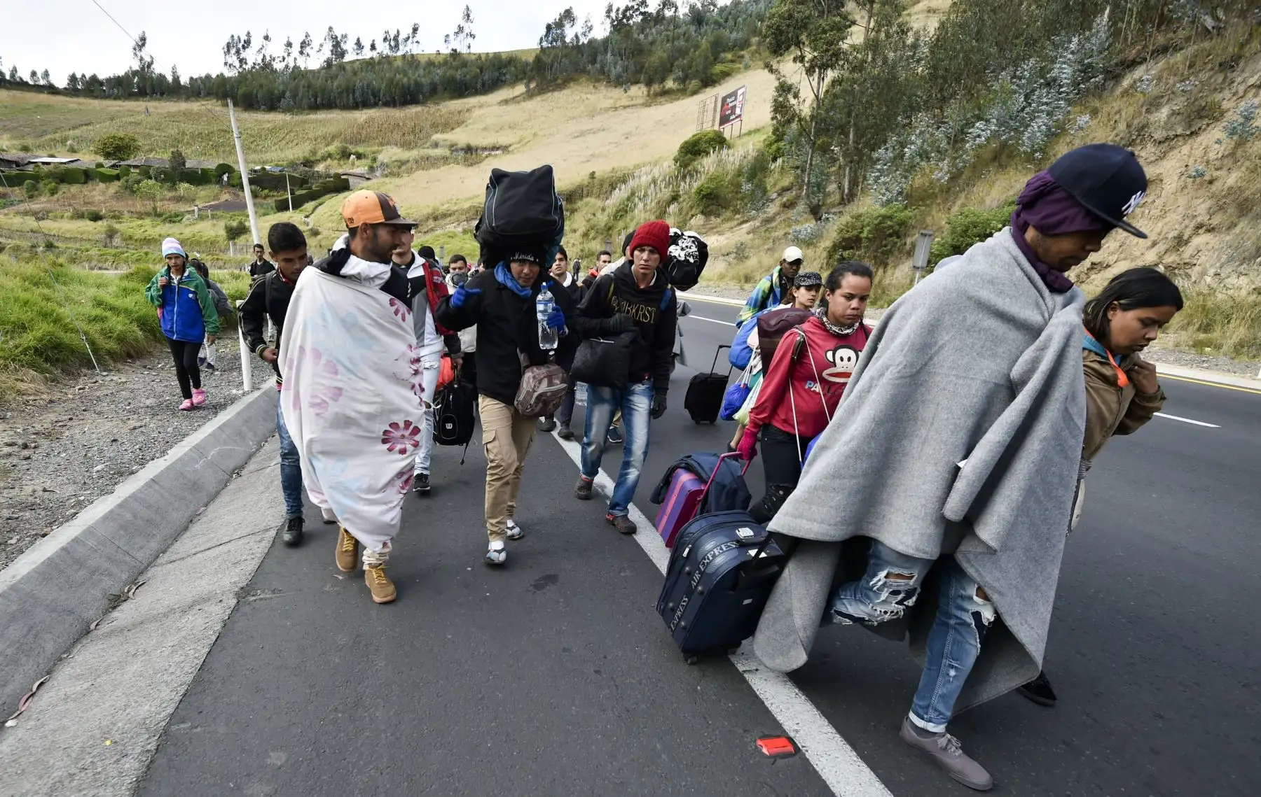 Los venezolanos que se dirigen a Perú caminan a lo largo de la carretera Panamericana en Tulcán, Ecuador, después de cruzar desde Colombia, el 21 de agosto de 2018.AFP