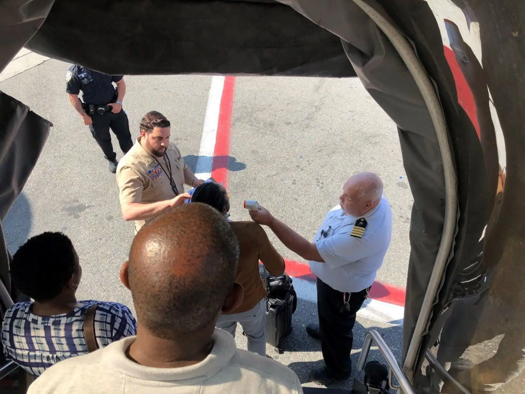 Imagen publicada con permiso vÌa Twitter, del usuario Larry Coben de una pasejera mientras le toman la temperatura al salir del vuelo Emirates 203 de Dubai, en el aeropuerto John F. Kennedy, en Queens, Nueva York, EEUU, el 5 de septiembre del 2018. Un aviÛn procedente de Dubai fue puesto hoy en cuarentena con varios centenares de personas abordo en el aeropuerto JFK de Nueva York, después de que al menos una decena de pasajeros se sintiesen enfermos, según informó la compañia Ìa Emirates. EFE