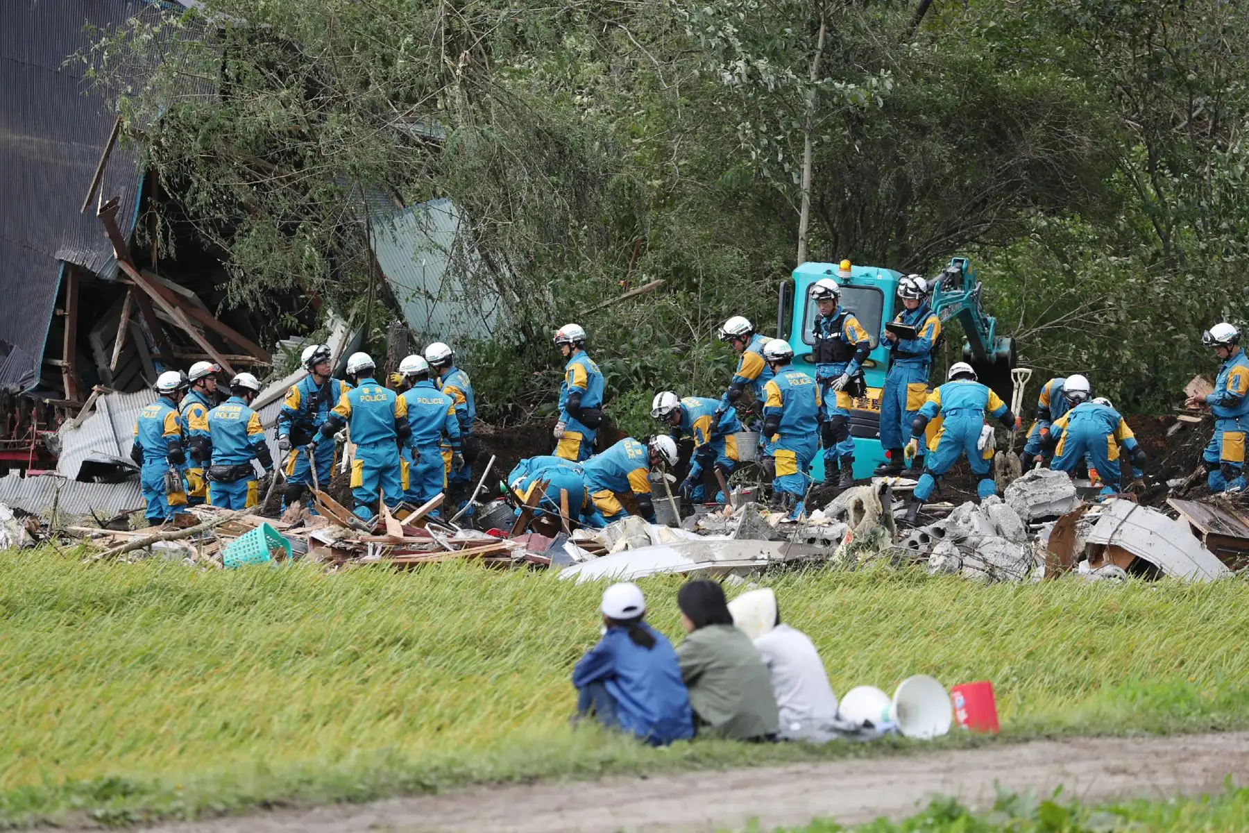 Los residentes locales observan cómo los equipos de rescate buscan personas desaparecidas en un área afectada por los deslizamientos de tierra provocados por un terremoto en la ciudad de Atsuma, prefectura de Hokkaido, el 7 de septiembre de 2018.
Los trabajadores de rescate japoneses con excavadoras y perros rastreadores buscaron en el barro el 6 de septiembre para encontrar sobrevivientes de un deslizamiento de tierra que enterró casas después de un poderoso terremoto, ya que el número de muertos aumentó