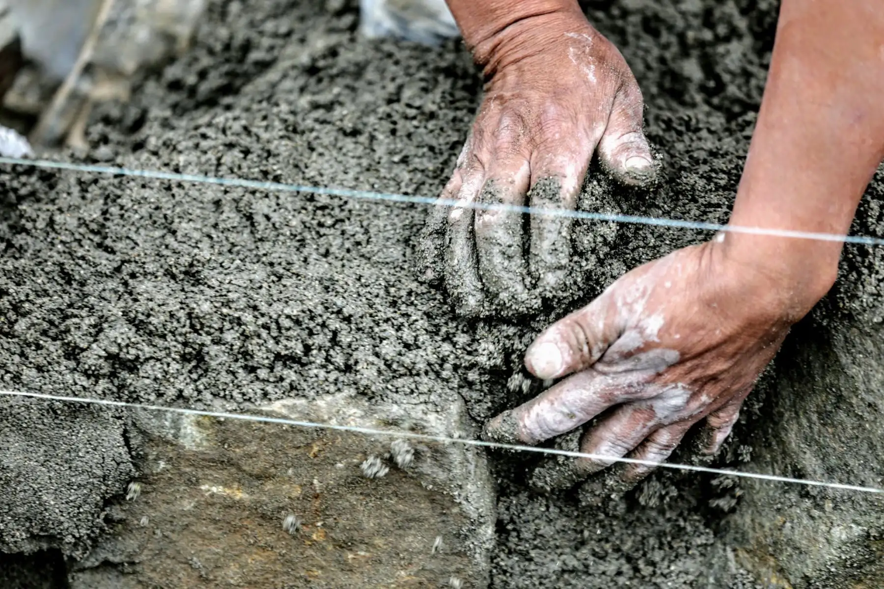 Las mujeres elaboran la mezcla de cemento, que, a su vez, servirá para el asentado de piedra y el solaqueo del muro de contención  en el AAHH "7 de junio", en el distrito de Mi Perú, Callao. Foto: ANDINA/Luis Iparraguirre