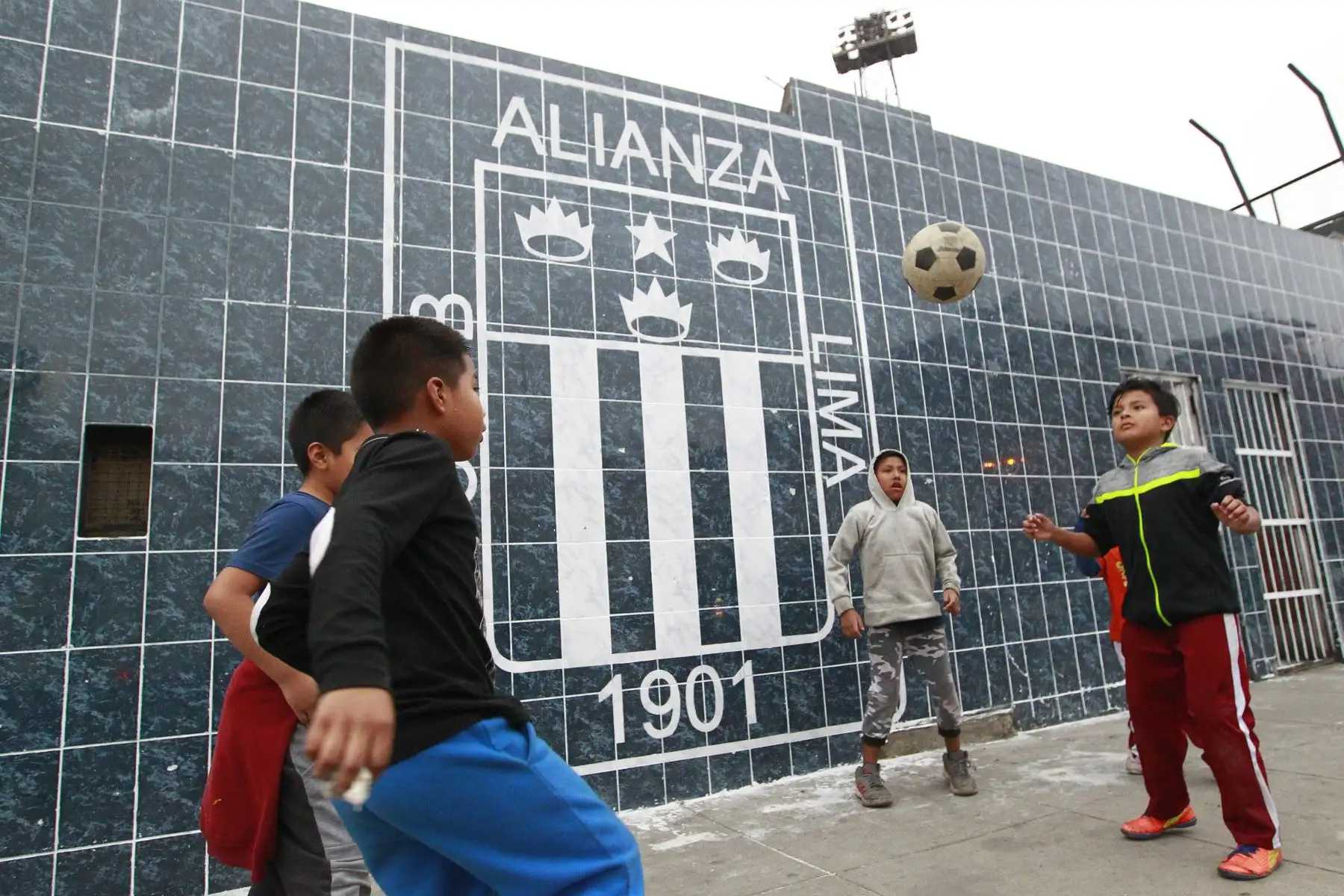 Niños aliancistas juegan en las afueras de  la explanada del  estadio de Alianza Lima, mientras hinchas adultos hacen la limpieza de los murales dañados.Foto: ANDINA/Eddy Ramos