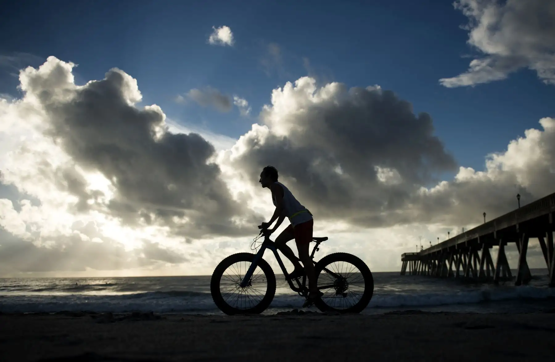 Una mujer monta en bicicleta en la playa un día antes de la llegada del huracán Florence a Wrightsville Beach, Carolina del Norte, el 12 de septiembre de 2018. AFP