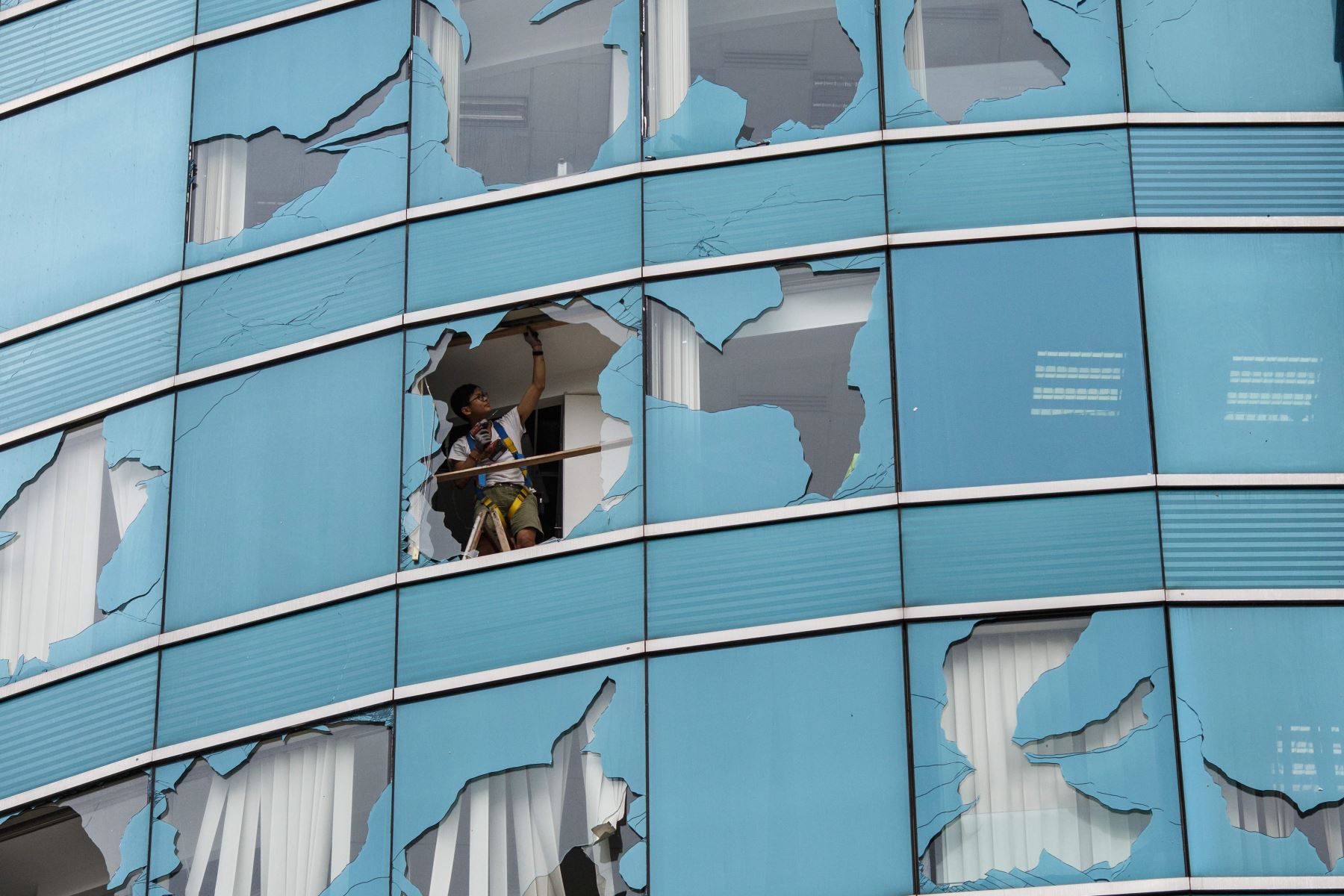 Trabajador repara una oficina en un edificio en Hong Kong luego del paso del tifón. Foto: AFP.