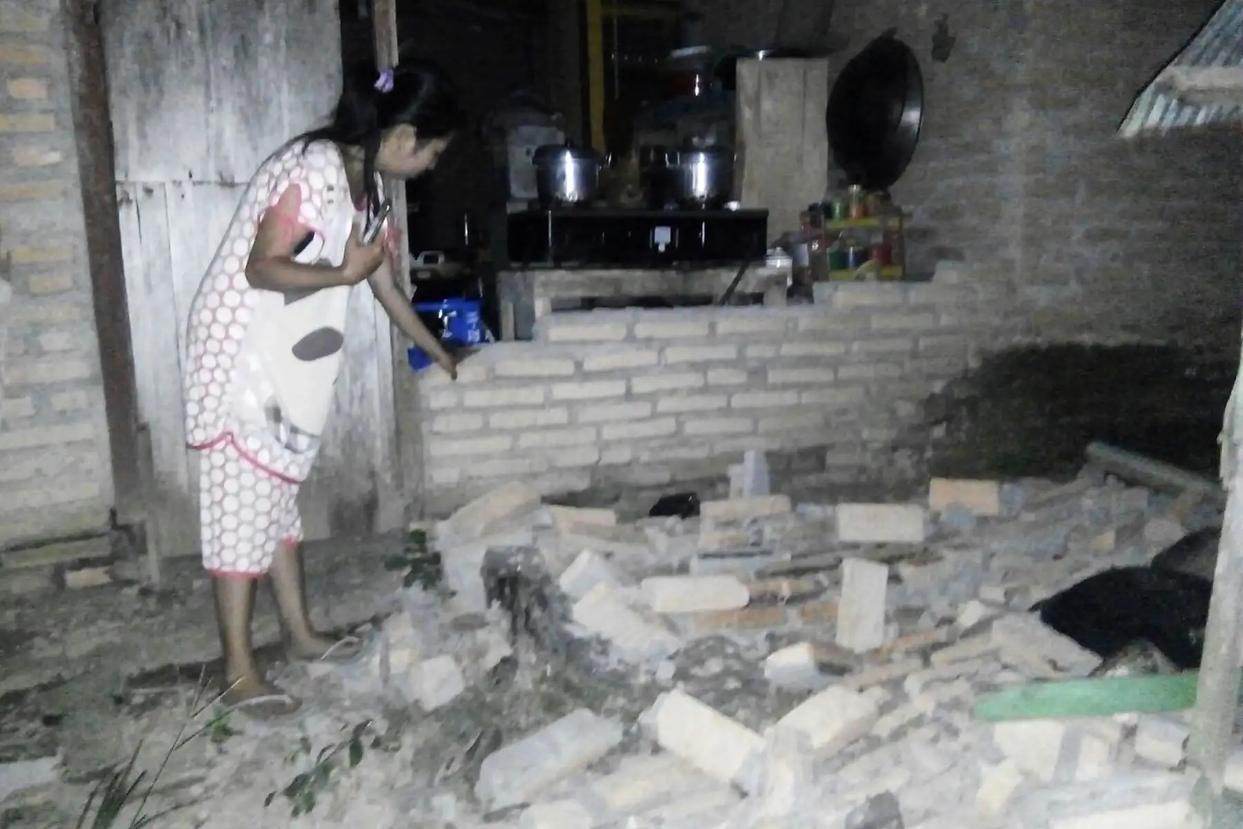 Un residente se ve al lado de la pared de ladrillo derrumbada de su casa en la aldea de Tobadak en Central Mamuju, provincia occidental de Sulawesi, el 28 de septiembre de 2018, después de que un fuerte terremoto azotara la zona. AFP