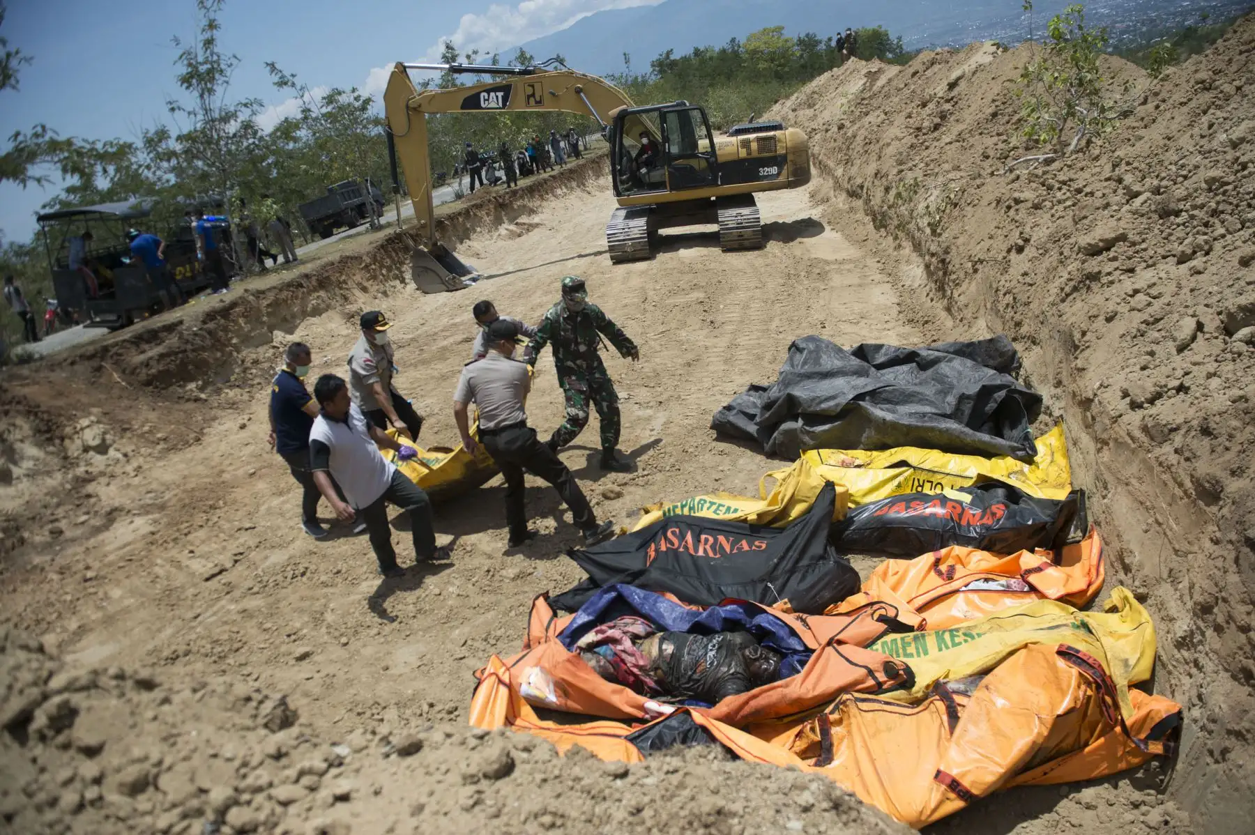 Los funcionarios llevan bolsas de cadáveres a una fosa común antes de un funeral masivo para las víctimas del terremoto en Palu, en Sulawesi Central, el 1 de octubre de 2018, después de un terremoto y un tsunami que azotaron la zona. AFP