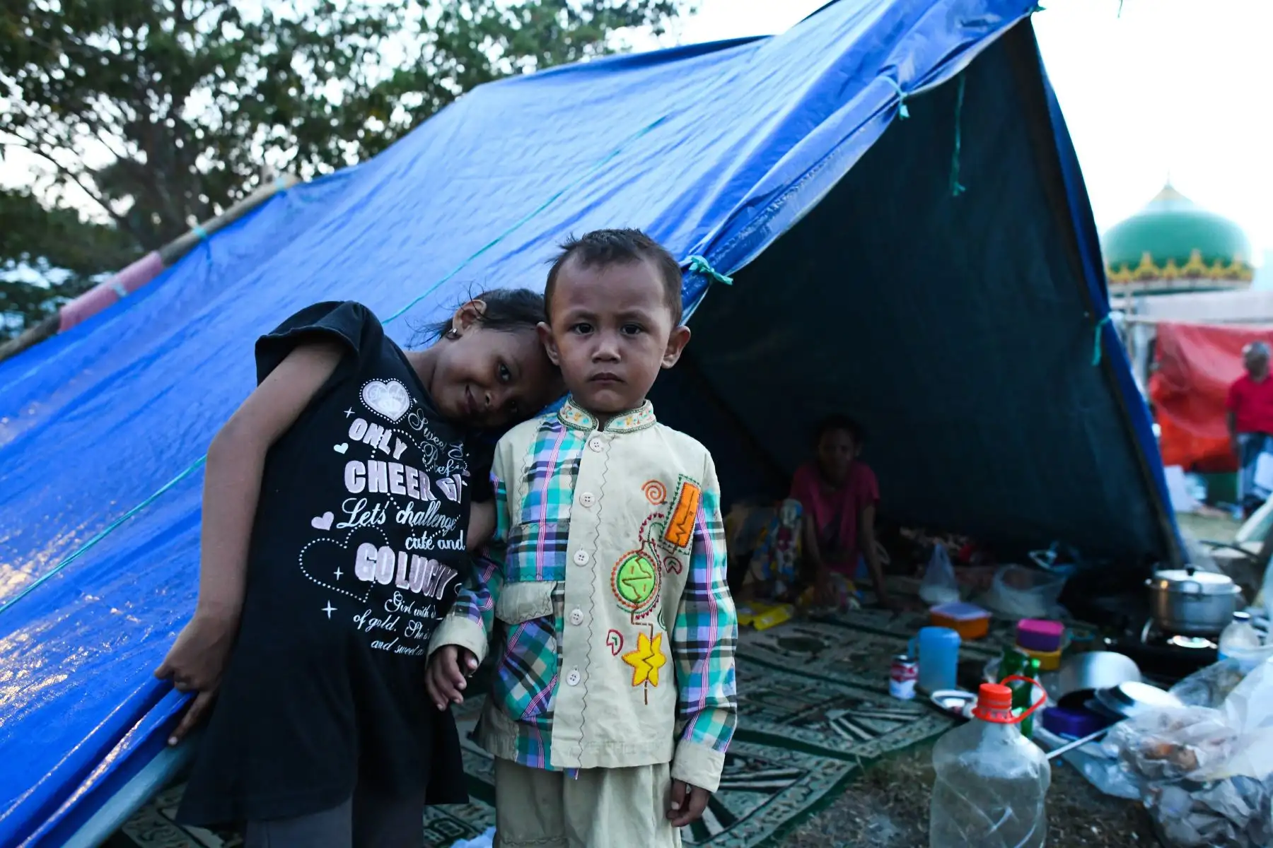 Los niños posan frente a una tienda de campaña en un campo de una mezquita donde se refugiaron en Palu, Sulawesi Central, Indonesia, el 1 de octubre de 2018, después de que un terremoto y un tsunami azotaran la zona. AFP