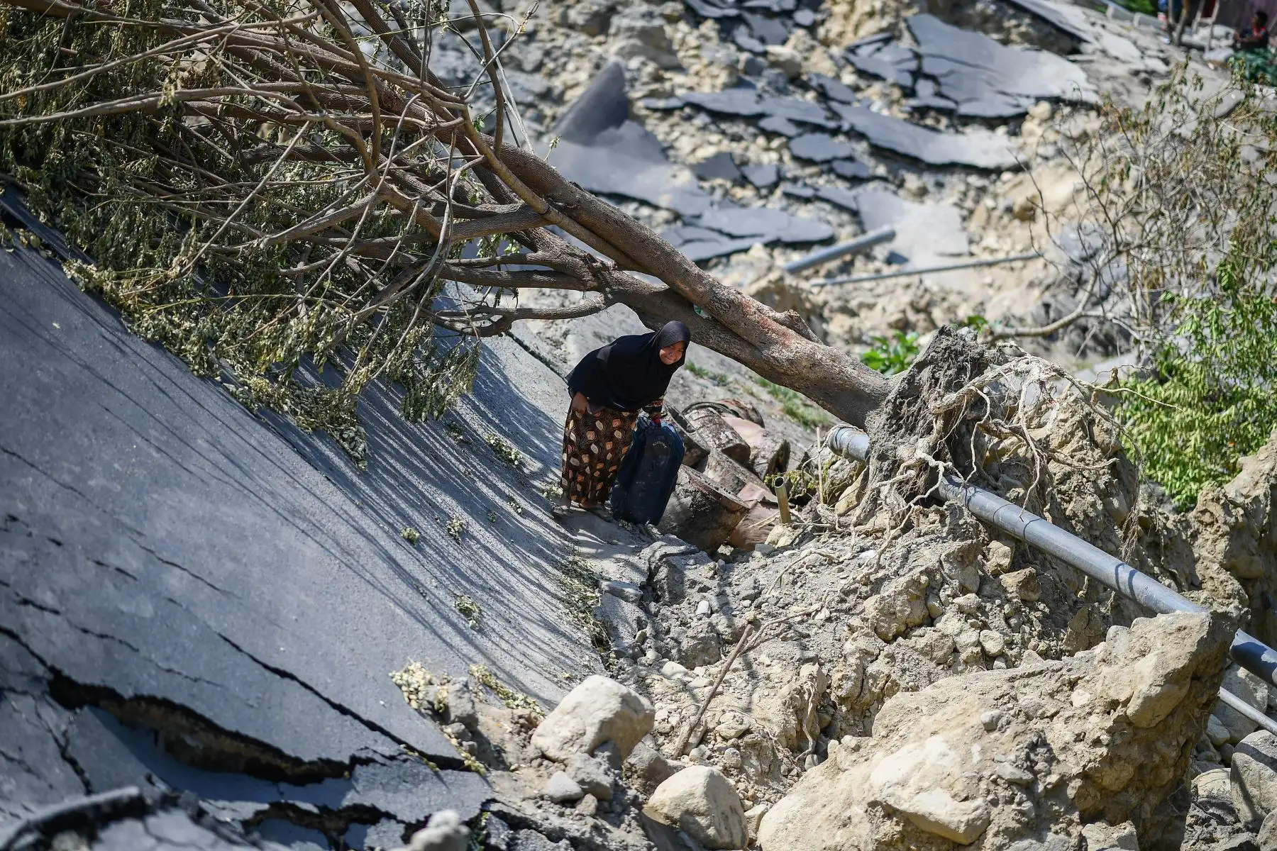 Una mujer con una maleta recorre una carretera destruida en Palu, Sulawesi Central de Indonesia, el 2 de octubre de 2018, después de que un terremoto y un tsunami azotaron el área el 28 de septiembre. AFP