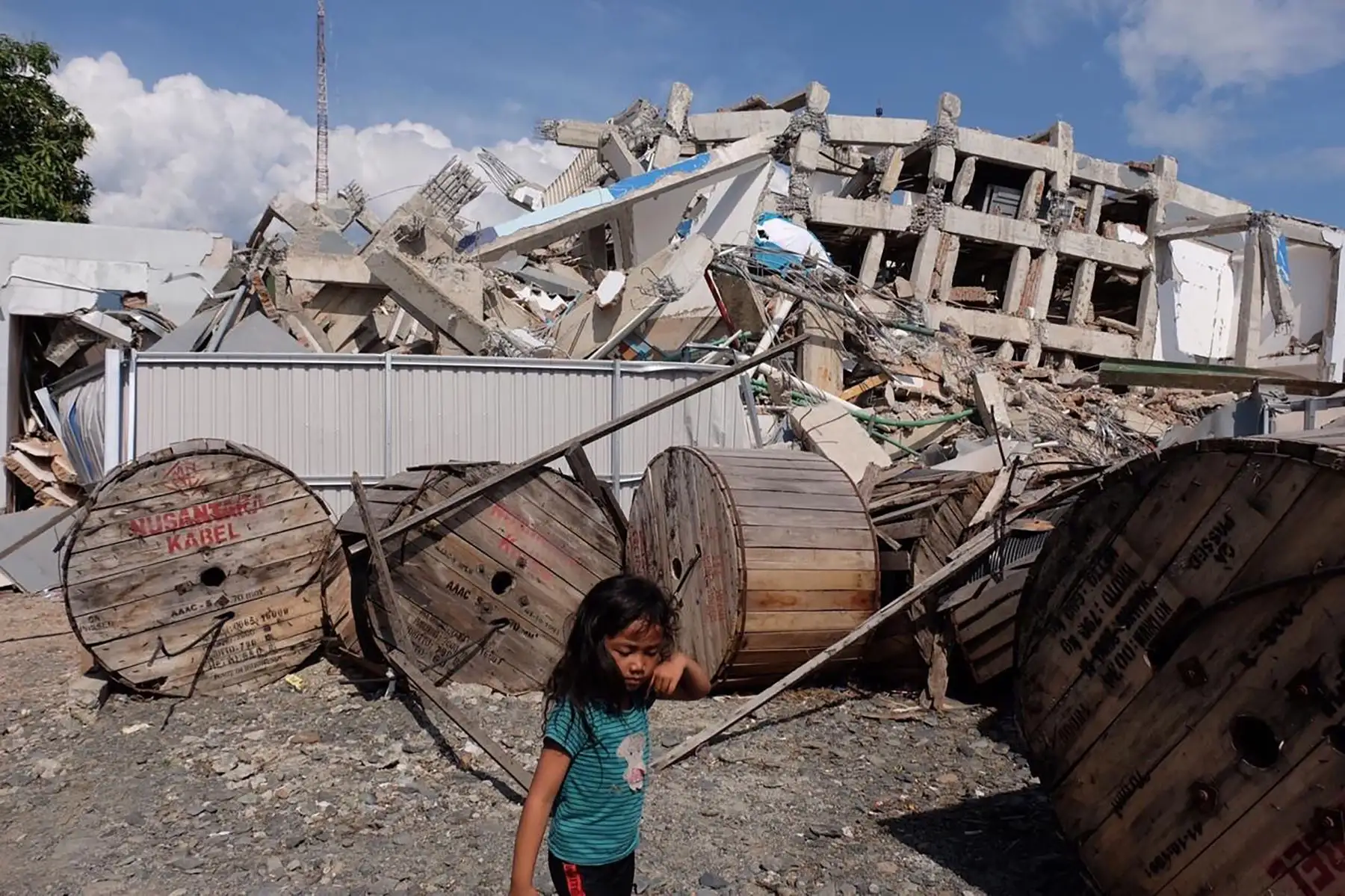 Un niño pasa junto a un edificio derrumbado en Palu, en Sulawesi Central de Indonesia, el 2 de octubre de 2018, después de que un terremoto y un tsunami azotaron el área el 28 de septiembre. AFP
