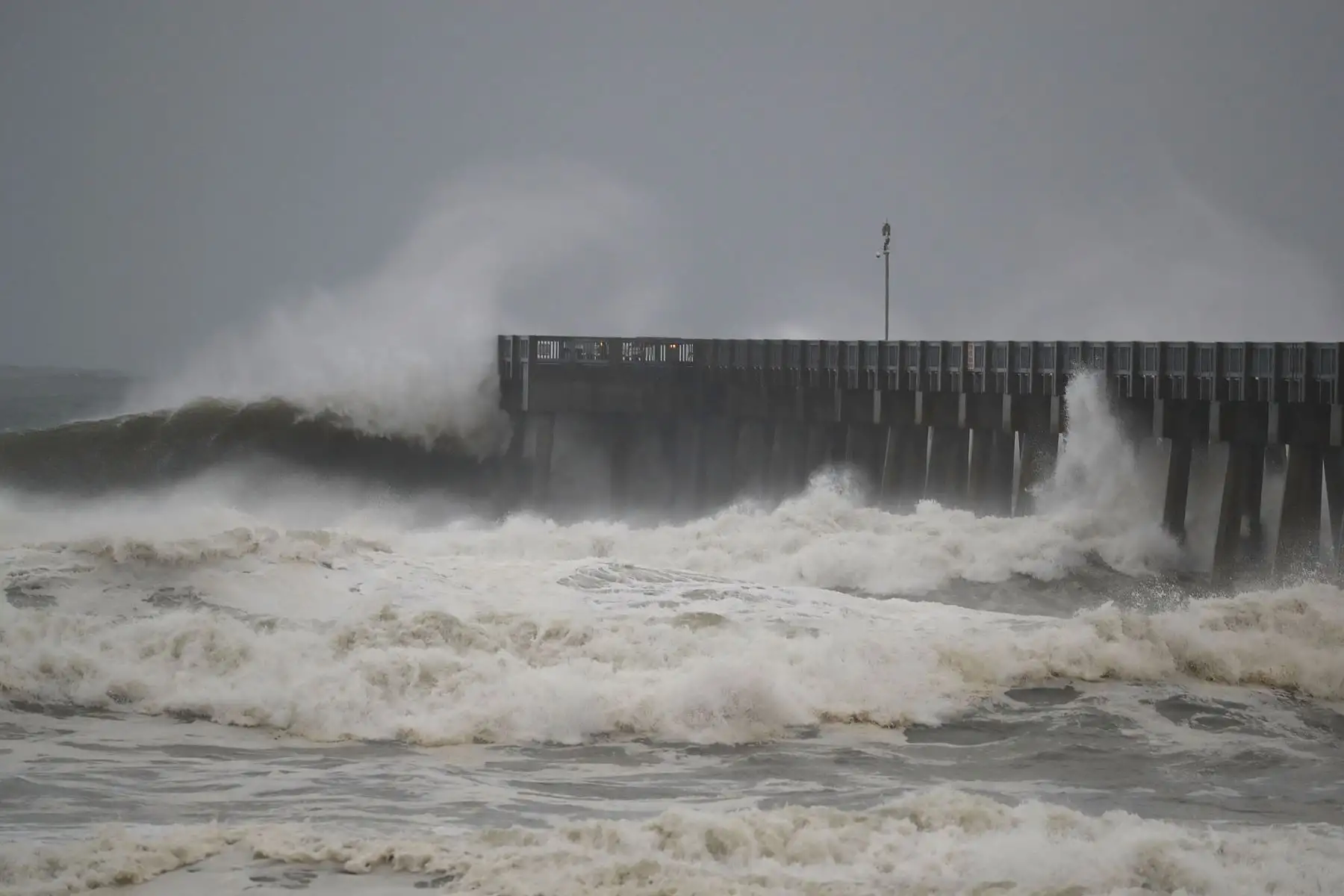 Las olas rompen a lo largo de un muelle cuando las bandas externas del huracán Michael llegan el 10 de octubre de 2018 a Panamá City Beach, Florida. Se pronostica que el huracán azotará el Panhandle de Florida en una posible tormenta de categoría 4. AFP
