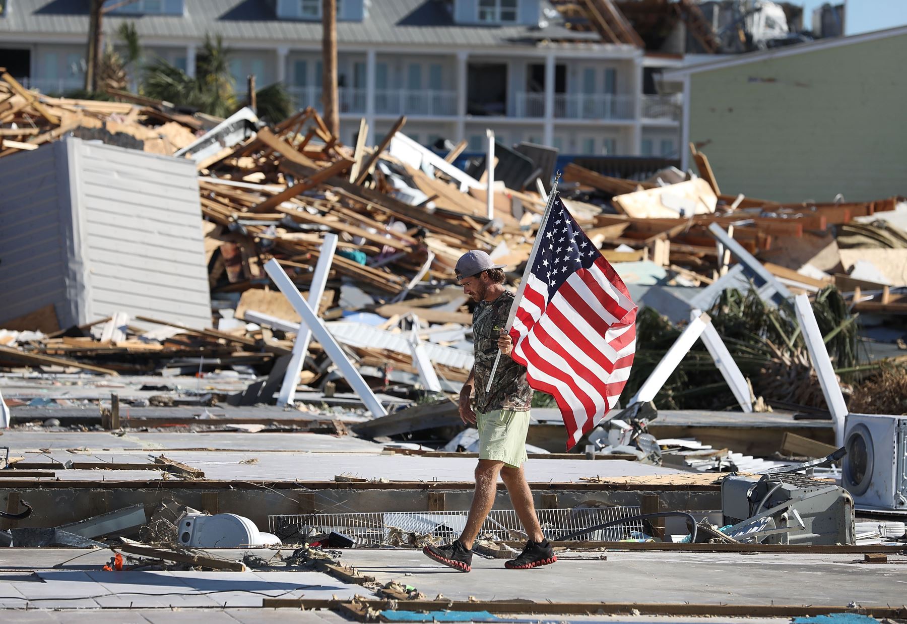 Kevin Guaranta lleva una bandera estadounidense que encontró mientras caminaba sobre los cimientos de las casas que fueron demolidas cuando el huracán Michael atravesó el área el 12 de octubre de 2018 en Mexico Beach, Florida. El huracán golpeó el área de los mangos con vientos de categoría 4 que causaron daños mayores. AFP