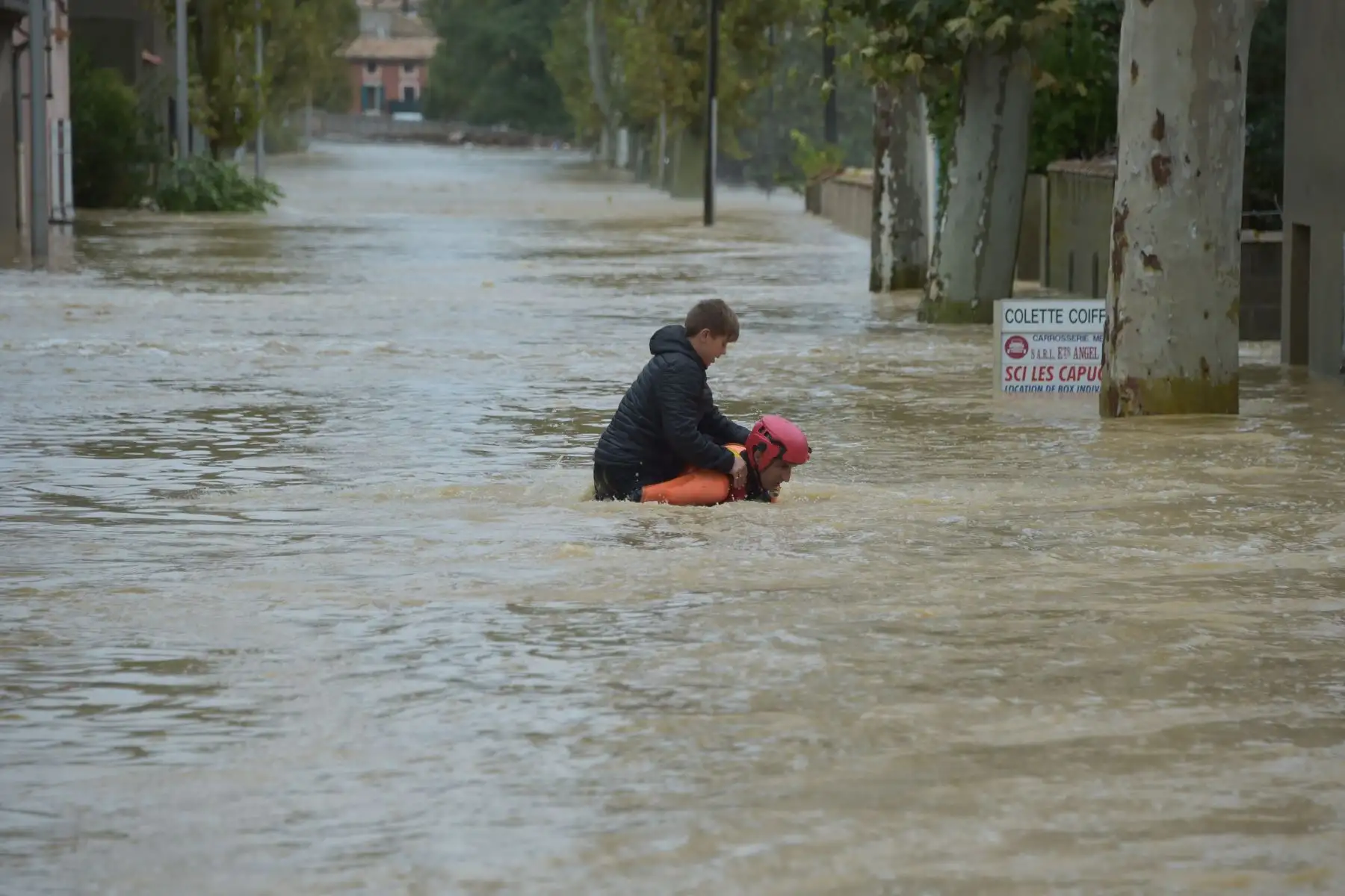 Un bombero ayuda a un joven a evacuar en una calle inundada durante una operación de rescate después de las fuertes lluvias que vieron cómo los ríos se desbordaban en Trebes, Francia.  AFP