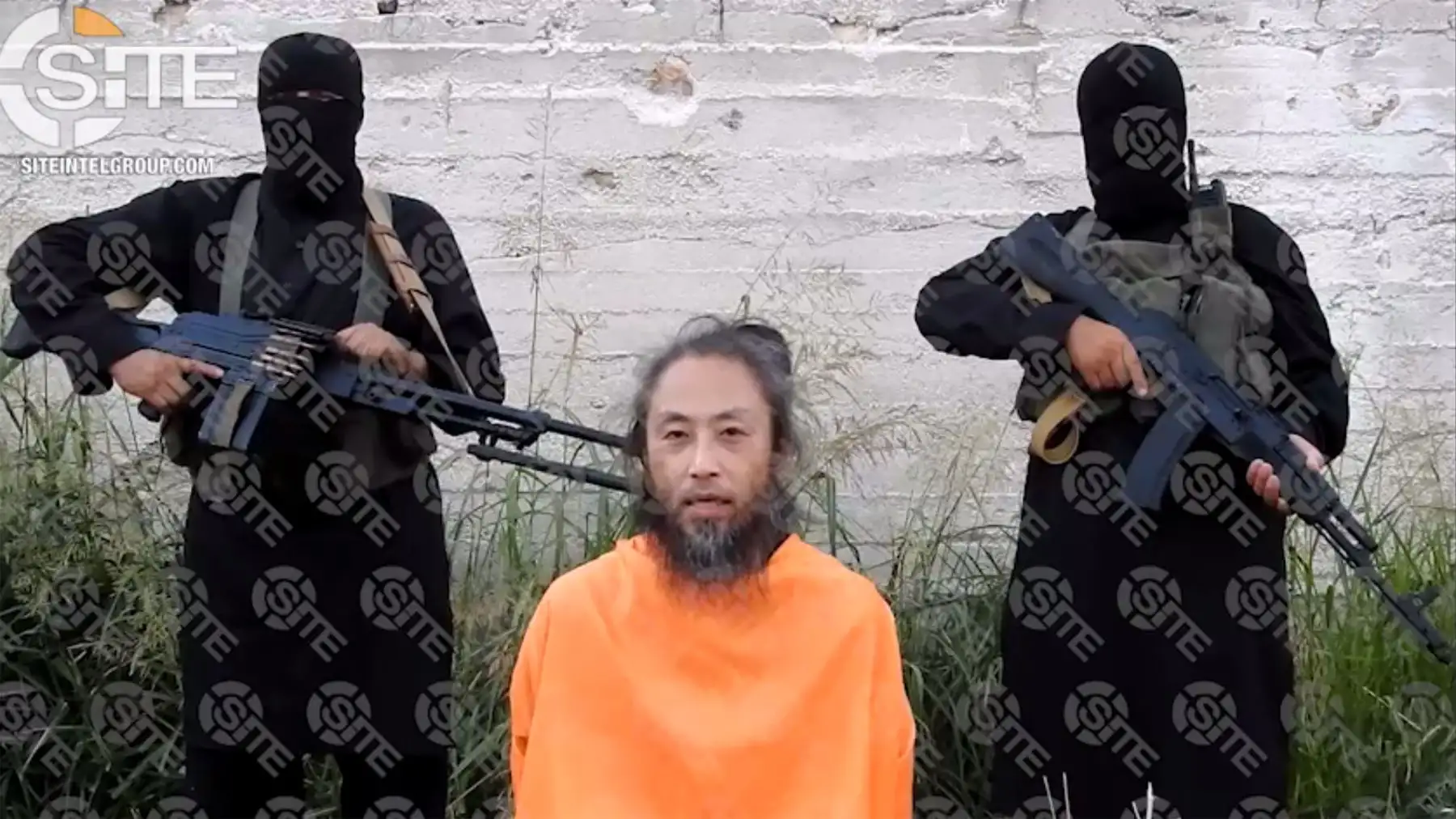 Esta imagen de video lanzada el 31 de julio de 2018, y cortesía de SITE Intelligence Group, muestra al ciudadano japonés, Yasuda Jumpei, solicitando su liberación mientras dos hombres armados lo respaldan en un lugar desconocido en Siria. Un grupo yihadista ha publicado videos de un periodista japonés y un italiano  cautivos en Siria en el que solicitan su liberación, dijeron monitores estadounidenses. AFP