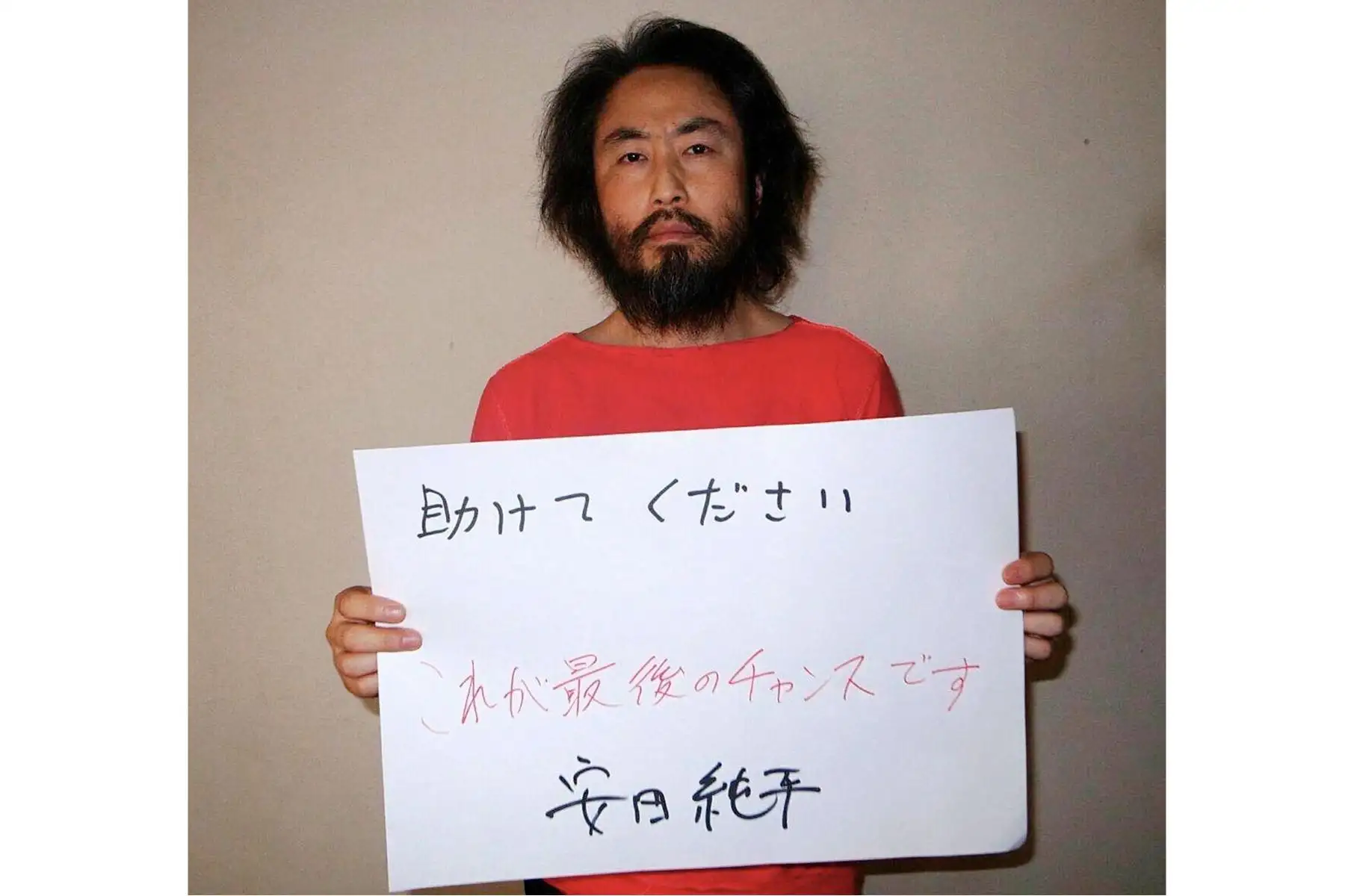 Esta fotografía sin fecha, proporcionada por la agencia de noticias japonesa Jiji Press, tomada en un lugar no revelado de Siria, fue emitida el 30 de mayo de 2016 y muestra al periodista independiente japonés Jumpei Yasuda sosteniendo un papel con un mensaje escrito a mano en japonés.  AFP