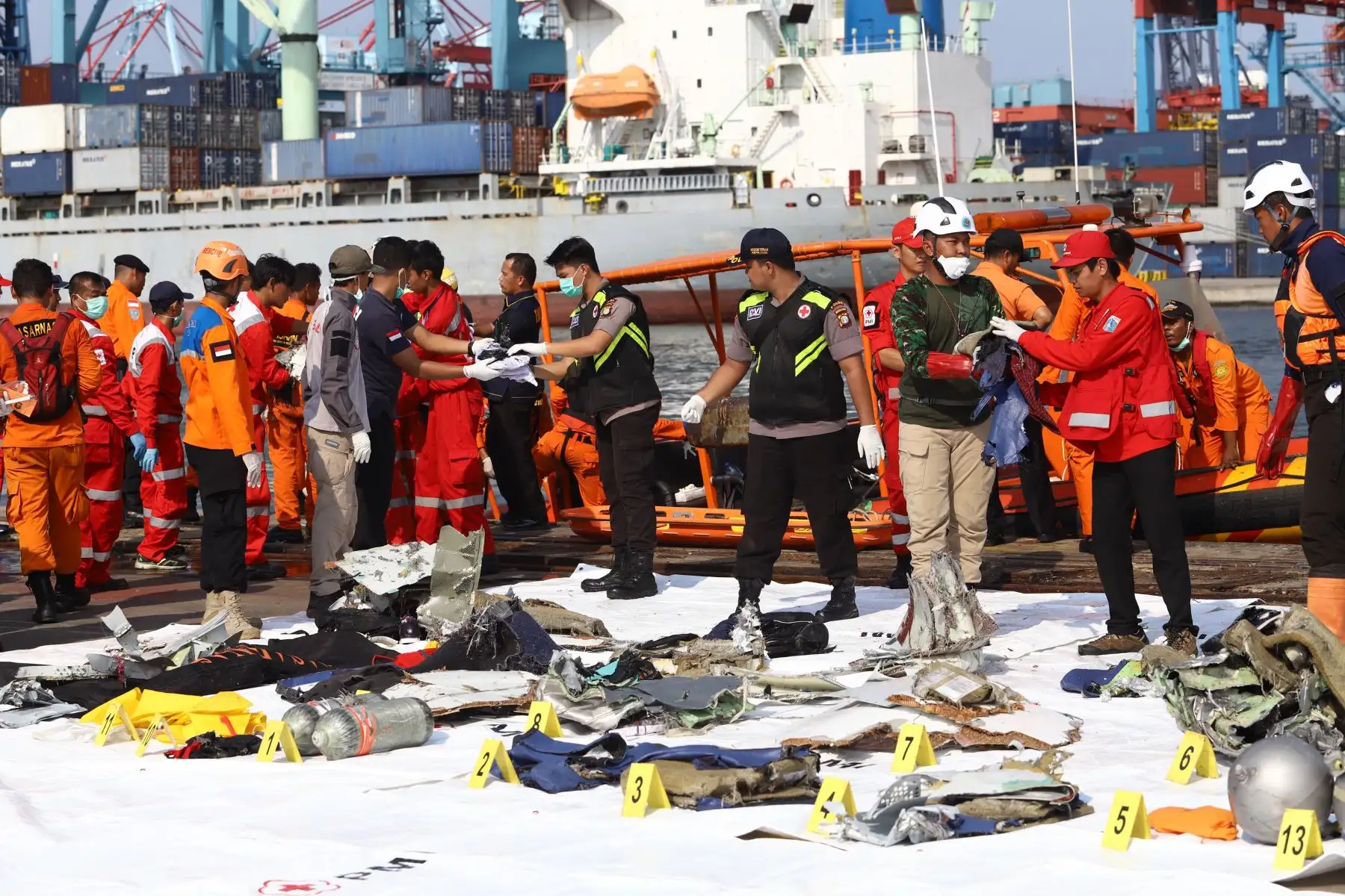 Los miembros de un equipo de rescate traen artículos personales y restos a tierra en el puerto de Tanjung Priok, norte de Yakarta, el 29 de octubre de 2018, después de que fueron recuperados del mar donde el vuelo JT 610 de Lion Air se estrelló frente a la costa norte. - Un nuevo avión indonesio Lion Air que transportaba a 189 pasajeros y tripulantes se estrelló en el mar el 29 de octubre, dijeron las autoridades, momentos después de haber solicitado que se le permitiera regresar a Yakarta.  AFP