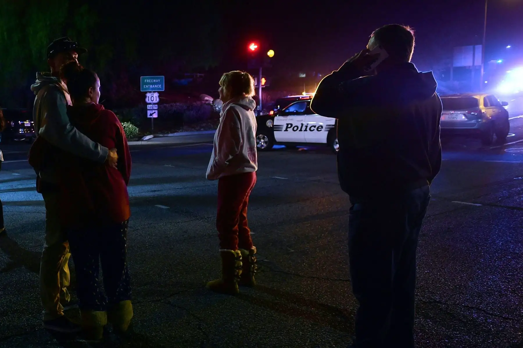Las personas se ponen de pie y observan cómo se despliega la escena desde la intersección de la autopista US 101 y la salida de Moorpark Rad mientras los vehículos de la policía cierran el área frente a un bar de música country y salón de baile en Thousand Oaks, al oeste de Los Ángeles, donde un hombre armado abrió fuego tarde El 7 de noviembre de 2018, matando al menos a 12 personas, dijo la policía estadounidense. AFP