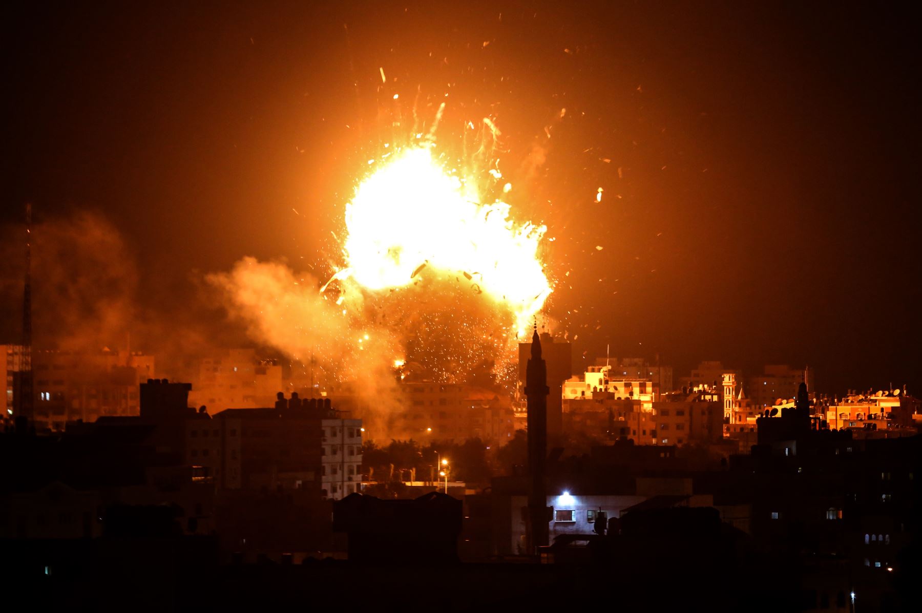 Una fotografía muestra una bola de fuego sobre el edificio que alberga la estación de televisión dirigida por Hamas al-Aqsa TV en la ciudad de Gaza durante un ataque aéreo israelí. - El ejército de Israel dijo que estaba llevando a cabo ataques aéreos "a lo largo de la Franja de Gaza" después del lanzamiento de cohetes desde el enclave palestino hacia su territorio. AFP