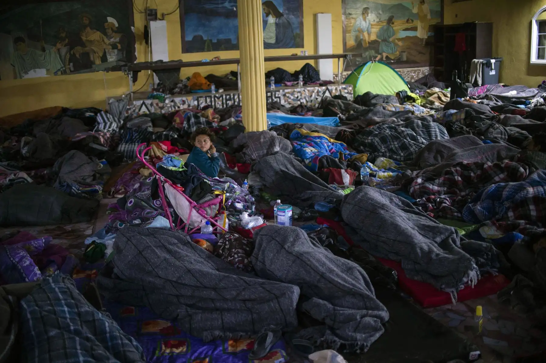 Los migrantes centroamericanos, en su mayoría hondureños, que se desplazan hacia los Estados Unidos con la esperanza de una vida mejor, permanecen en un refugio en Mexicali, estado de Baja California, México. El presidente de los Estados Unidos, Trump, envió a alrededor de 5,800 soldados a la frontera para prevenir la llegada de grandes grupos de migrantes centroamericanos que viajan a través de México y hacia los EE. UU., en una medida que los críticos denuncian como un truco político costoso para impulsar