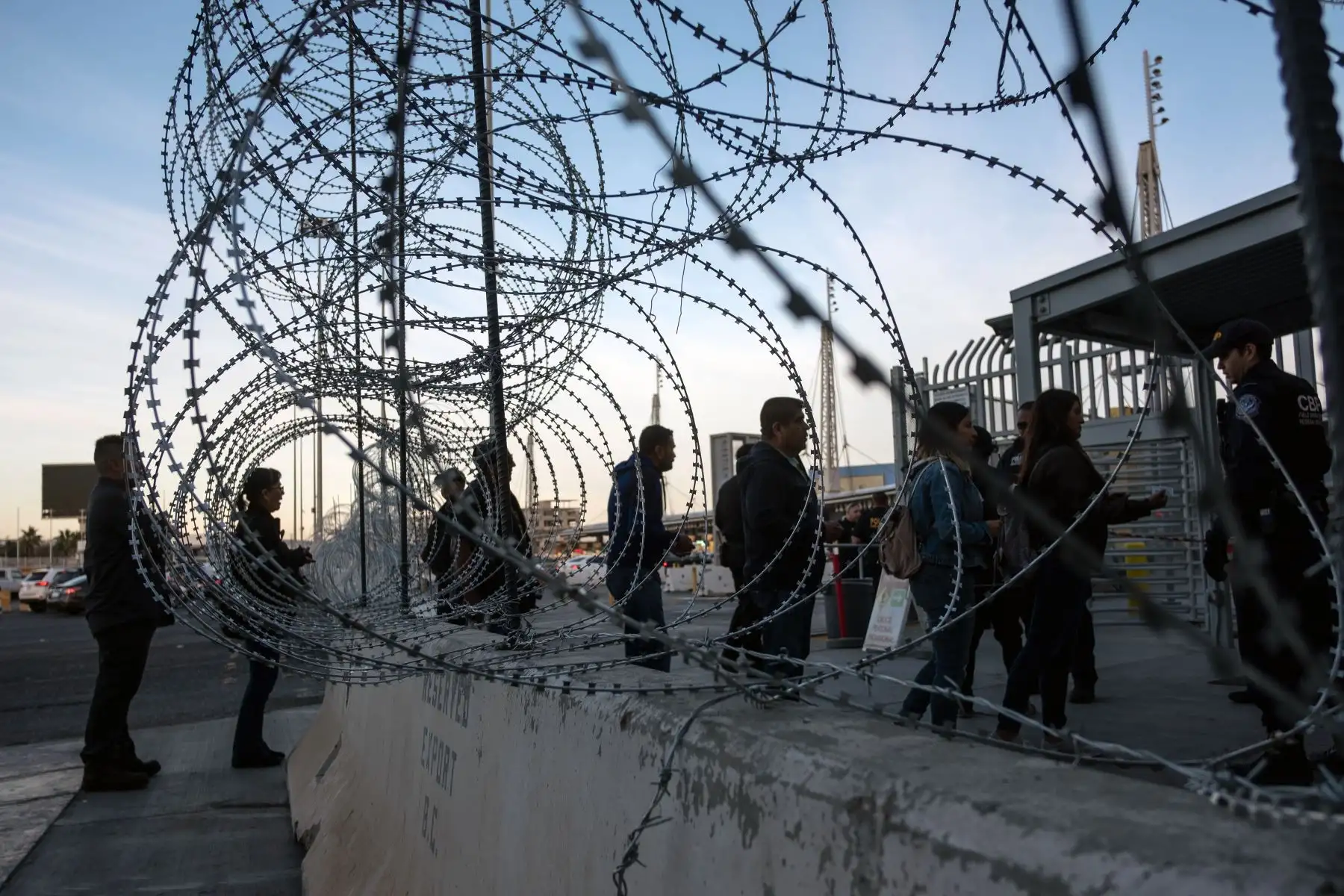 Un oficial de Aduanas y Protección Fronteriza les pide a los viajeros sus visas según se ven a través de las barreras establecidas por las autoridades de los EE. UU. En el puerto de entrada de San Ysidro, en la frontera de México y Estados Unidos, en preparación para la llegada de una caravana de migrantes centroamericanos que se dirige a los Estados Unidos. , visto desde Tijuana, México, El presidente de los EE. UU., Trump, envió alrededor de 5,800 soldados a la frontera para prevenir la llegada de grandes