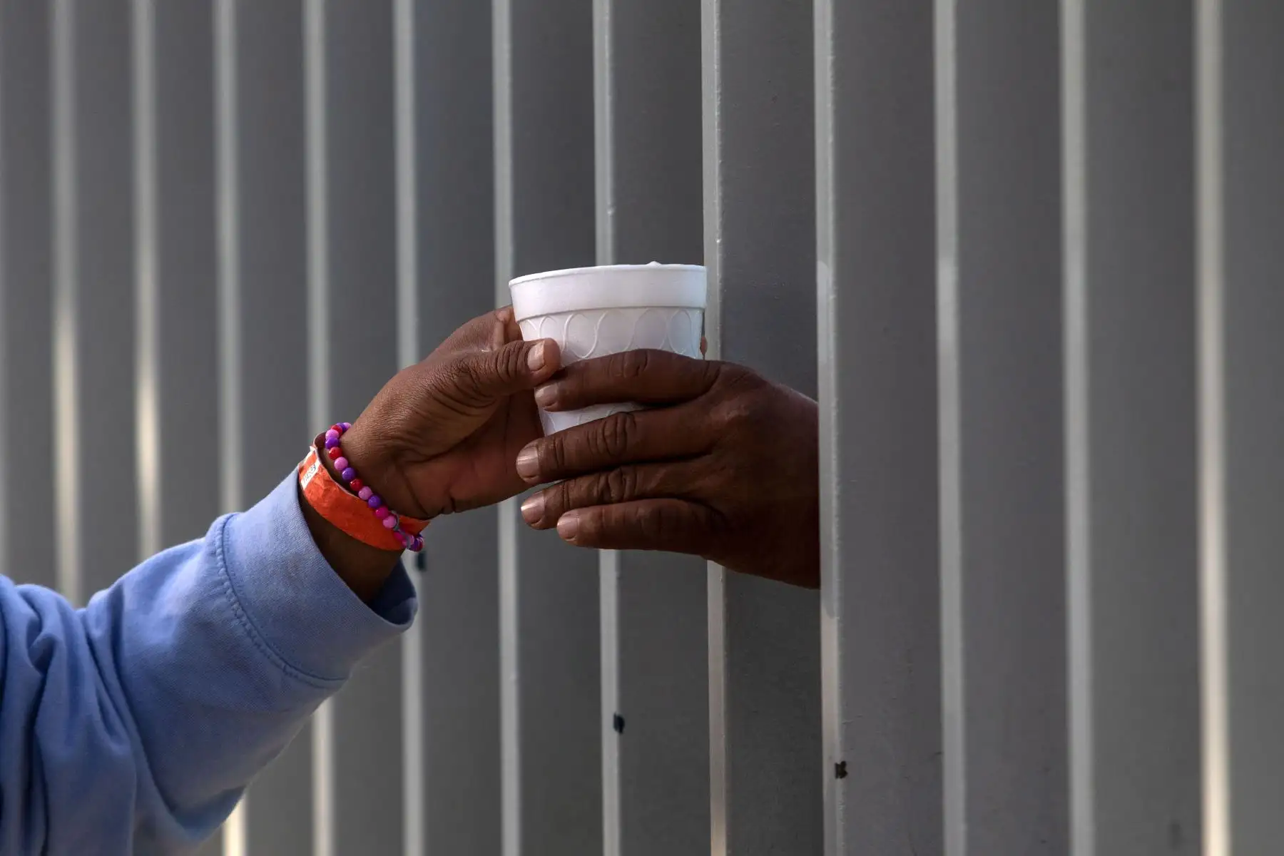 Un migrante que viaja con otros migrantes centroamericanos, principalmente hondureños, que se dirige a los Estados Unidos con la esperanza de una vida mejor, compra una taza de chocolate caliente a través de la cerca de un refugio en Tijuana, México. El Presidente de los Estados Unidos Trump ha enviado alrededor de 5,800 soldados a la frontera para prevenir la llegada de grandes grupos de migrantes centroamericanos que viajan a través de México y hacia los EE. UU., En un movimiento que los críticos denuncia