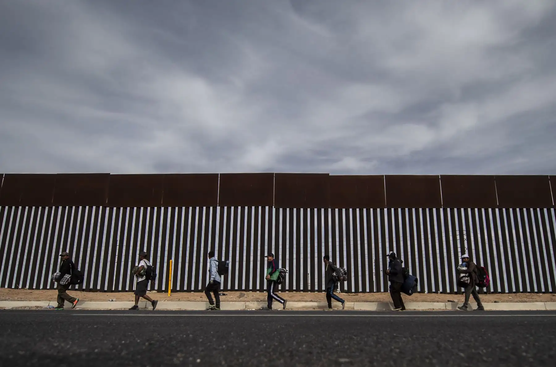Los migrantes centroamericanos, en su mayoría hondureños, que se desplazan en caravana hacia Estados Unidos con la esperanza de una vida mejor, caminan a lo largo de la valla metálica en la frontera entre Mexicali en el estado mexicano de Baja California y Calexico, en California, EE. UU. - El presidente de los Estados Unidos, Trump, envió alrededor de 5,800 soldados a la frontera para prevenir la llegada de grandes grupos de migrantes centroamericanos que viajan a través de México y hacia los EE. UU., En u
