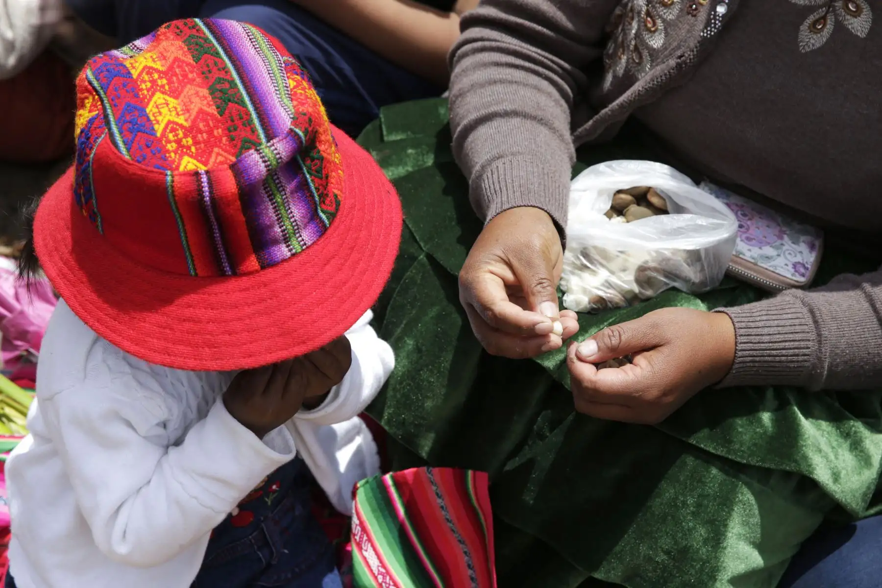 Niño es alimentado por su madre con habas, mientras esperan el paso de  la comparsa. Foto: ANDINA/Melina Mejía