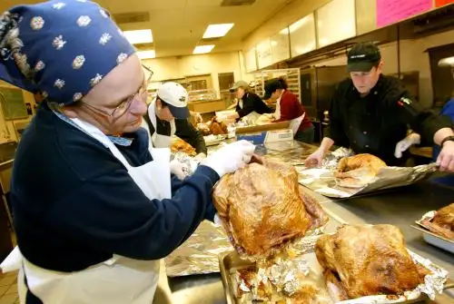 Los voluntarios ayudan a preparar cenas de pavo para personas. AFP