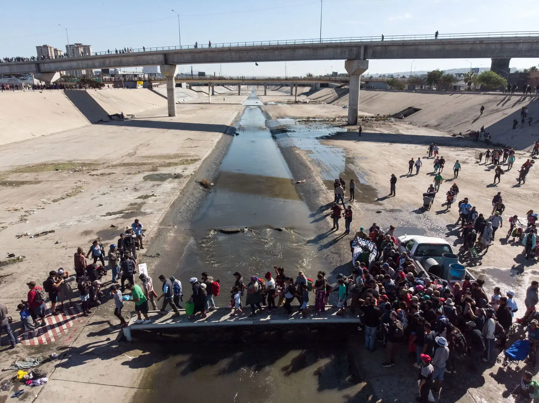 Un grupo de migrantes centroamericanos, principalmente de Honduras, corre a lo largo del lecho seco del río Tijuana en un intento por llegar al puerto de entrada de El Chaparral, en Tijuana, estado de Baja California, México, cerca de la frontera entre Estados Unidos y México. Cientos de migrantes intentaron asaltar una cerca fronteriza que separa a México de los EE. UU. El domingo en medio de crecientes temores de que se queden en México mientras se procesan sus solicitudes de asilo. Un fotógrafo de la AFP
