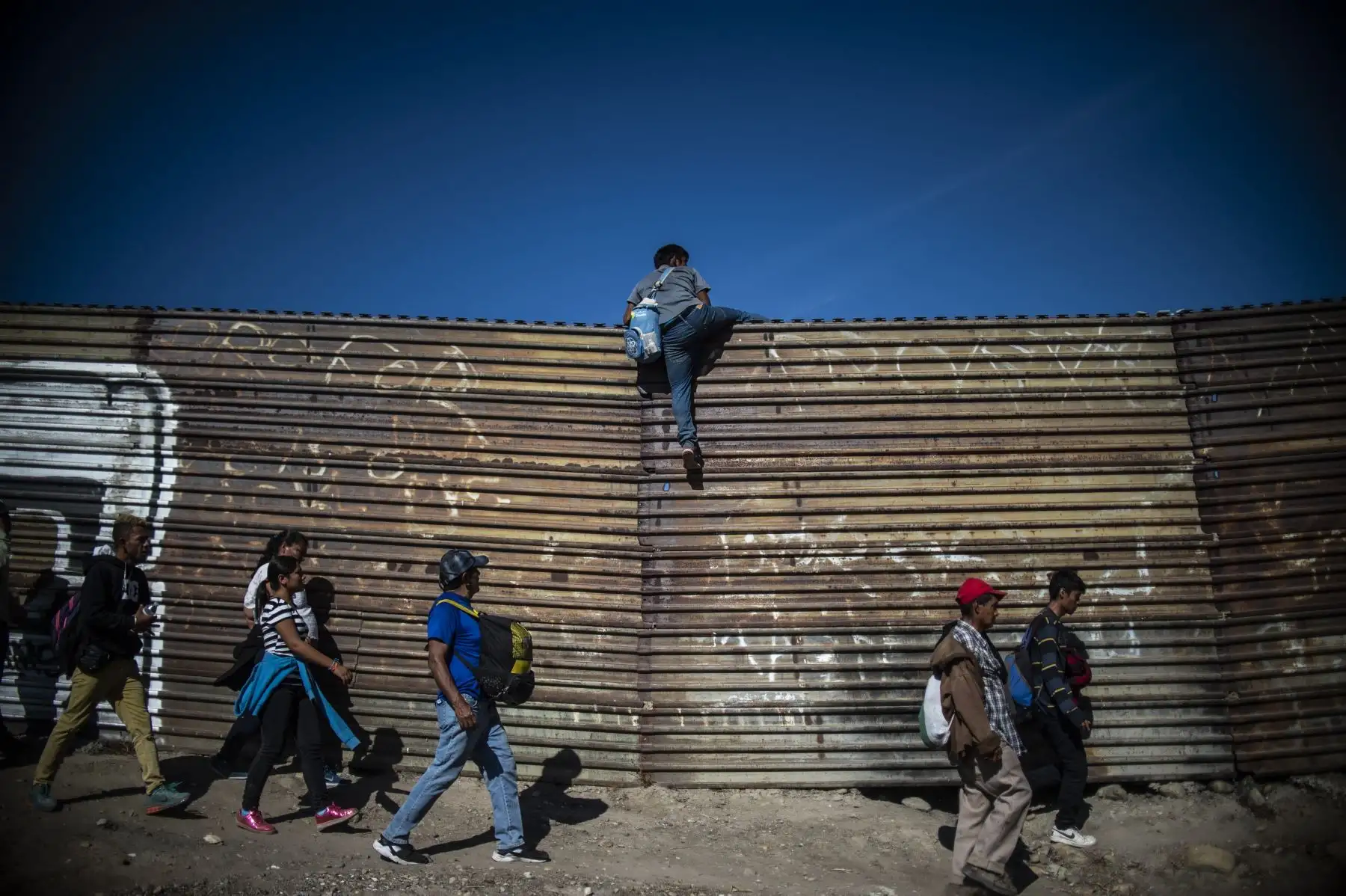 Un grupo de migrantes centroamericanos, en su mayoría hondureños, trepan la frontera entre México y Estados Unidos, cerca del cruce de El Chaparral, en Tijuana, estado de Baja California, México. Cientos de migrantes intentaron asaltar una La cerca fronteriza que separa a México de los EE. UU. el domingo en medio de crecientes temores de que se queden en México mientras se procesan sus solicitudes de asilo. Un fotógrafo de la AFP dijo que los migrantes se separaron de una marcha pacífica en un puente fronter