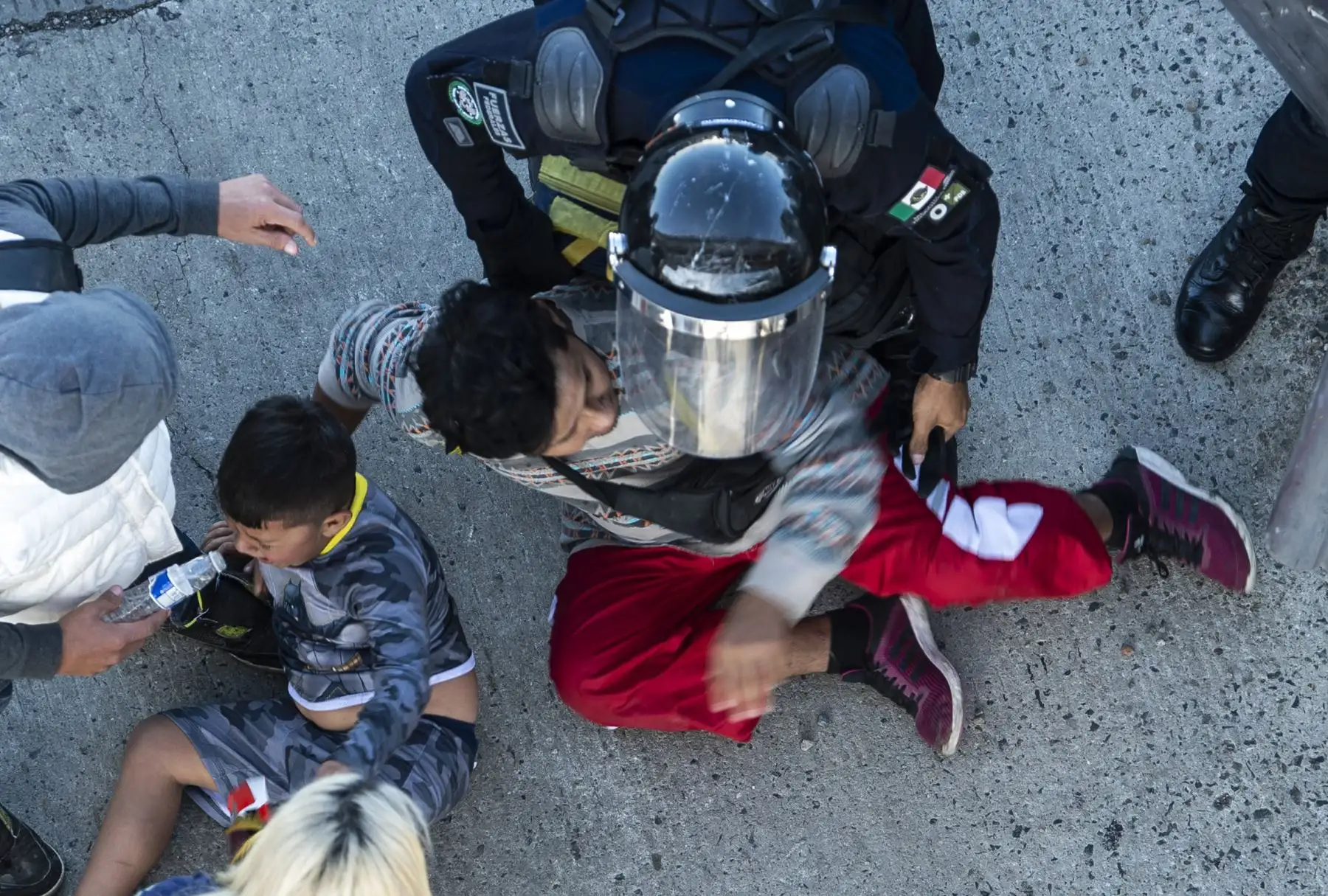 Los migrantes centroamericanos son detenidos por las fuerzas policiales mexicanas cuando llegan al cruce fronterizo de El Chaparral, en Tijuana, estado de Baja California, México. Cientos de migrantes intentaron asaltar una cerca fronteriza que separa a México de los EE. UU. En medio de crecientes temores, se mantendrán en México mientras se procesan sus solicitudes de asilo. Un fotógrafo de la AFP dijo que los migrantes se separaron de una marcha pacífica en un puente fronterizo e intentaron escalar una ba
