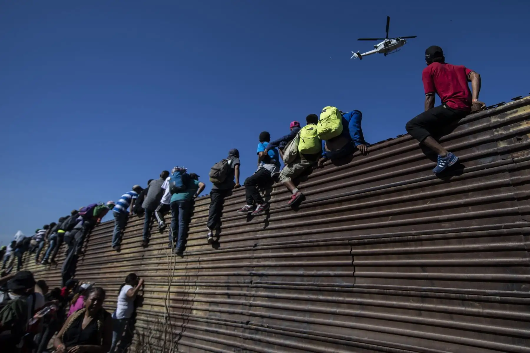 Un grupo de migrantes centroamericanos, en su mayoría hondureños, escalan una barrera de metal en la frontera entre México y EE. UU. Cerca del cruce fronterizo de El Chaparral, en Tijuana, estado de Baja California, México. Las autoridades estadounidenses cerraron el cruce de San Ysidro. El domingo, en el sur de California, después de cientos de migrantes, parte de la "caravana" condenada por el presidente Donald Trump, trató de romper una cerca de Tijuana, anunciaron las autoridades. AFP