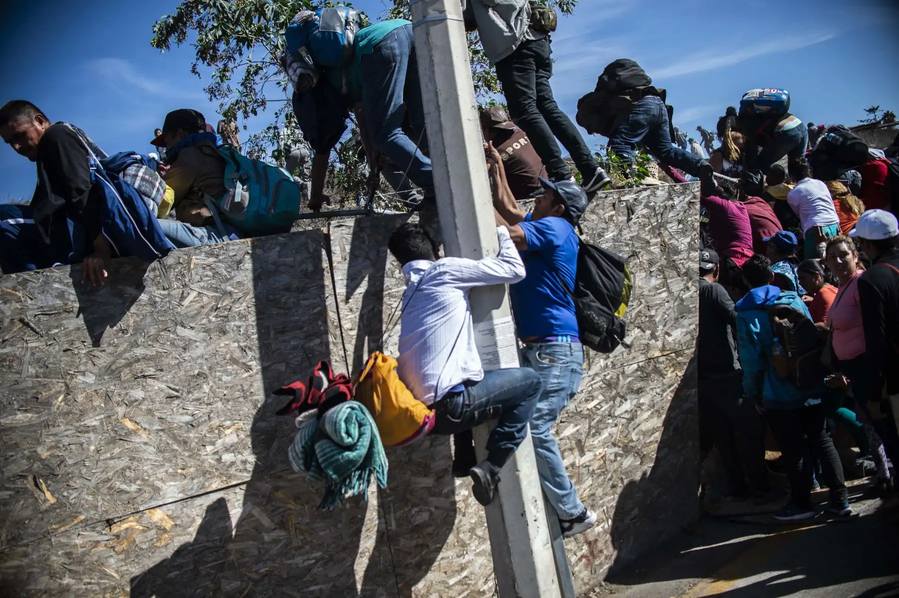 Un grupo de migrantes centroamericanos, en su mayoría hondureños, se sobrepasan cuando intentan llegar a la frontera entre México y Estados Unidos cerca del cruce de El Chaparral en Tijuana, estado de Baja California, México. Cientos de migrantes Intentó asaltar una valla fronteriza que separa a México de los EE. UU. el domingo, en medio de crecientes temores de que se queden en México mientras se procesan sus solicitudes de asilo. Un fotógrafo de la AFP dijo que los migrantes se separaron de una marcha pac