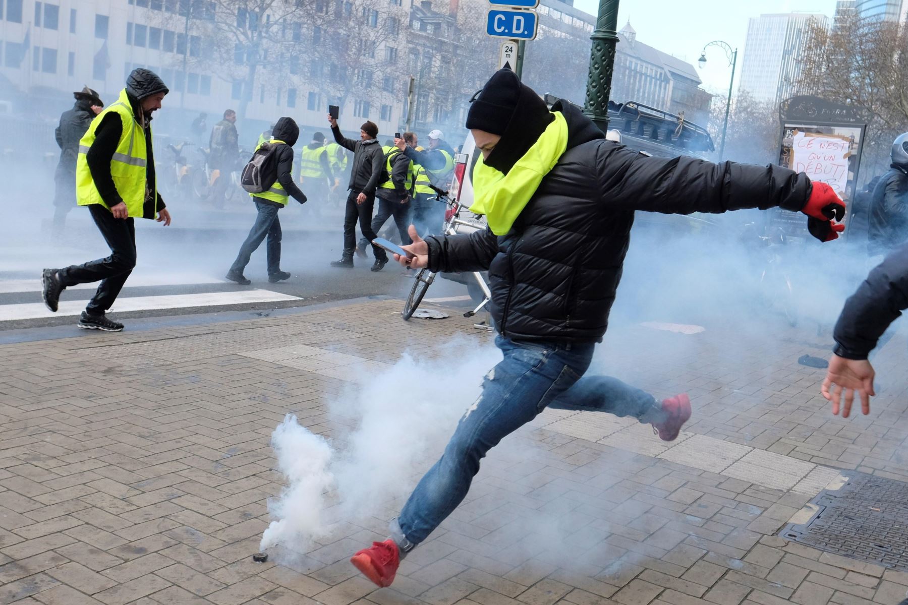 Un manifestante del colectivo "chalecos amarillos" trata de devolver un cartucho de gas lacrimógeno Foto: EFE