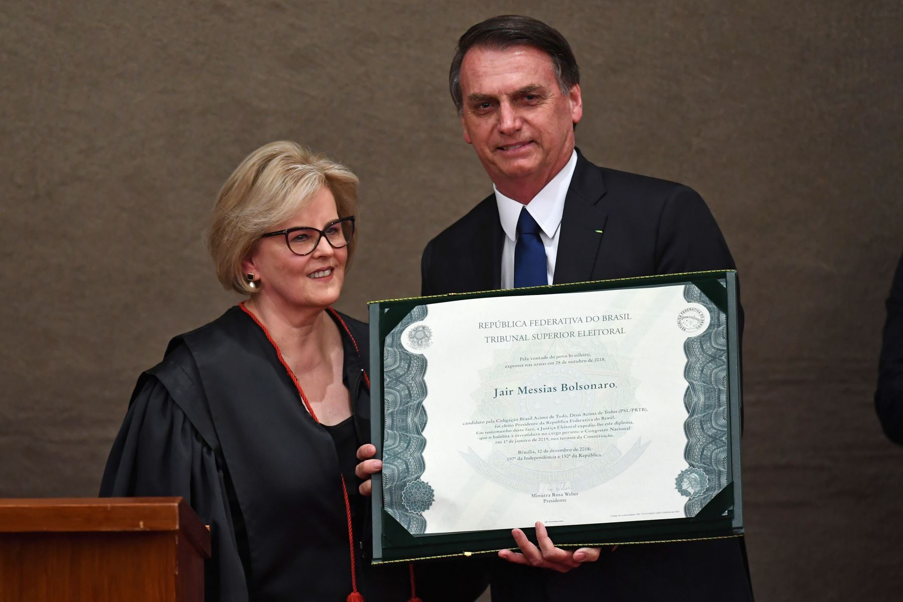 Jair Bolsonaro, exhibe un diploma que certifica que puede asumir el cargo como presidente, junto a la presidenta de la Corte Suprema Electoral, la jueza Rosa Weber Foto: EFE