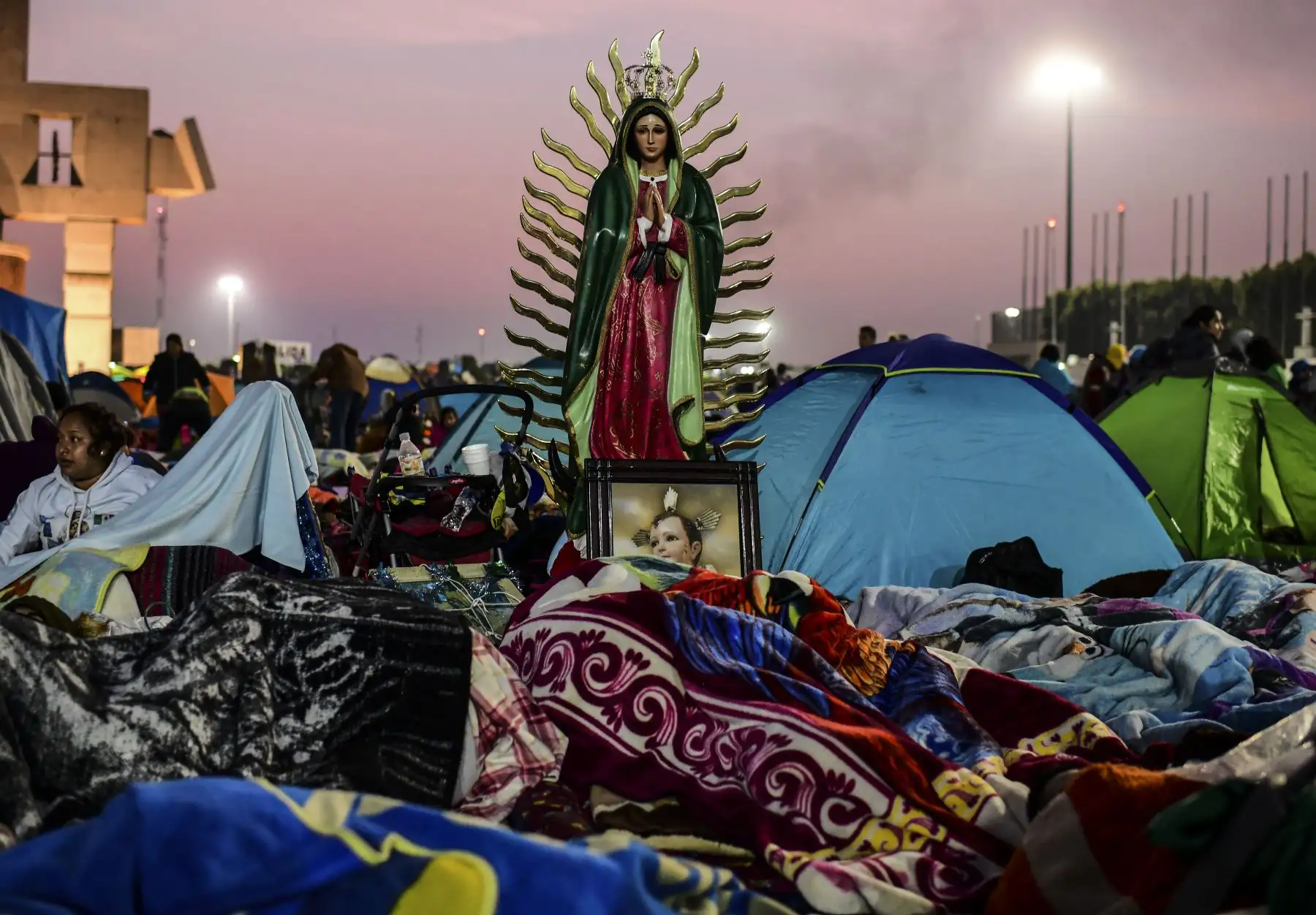 Los peregrinos duermen cerca de una imagen de la Virgen de Guadalupe, durante las celebraciones anuales en la Basílica de Guadalupe en la Ciudad de México, el 12 de diciembre de 2018. - Cientos de miles de peregrinos completan su viaje anual a la Basílica de Nuestra Señora de Guadalupe en México. para celebrar la fecha en que, según la tradición católico-romana, la Virgen se apareció a San Juan Diego hablando en su idioma nativo náhuatl en la montaña de Tepeyac en 1531. AFP