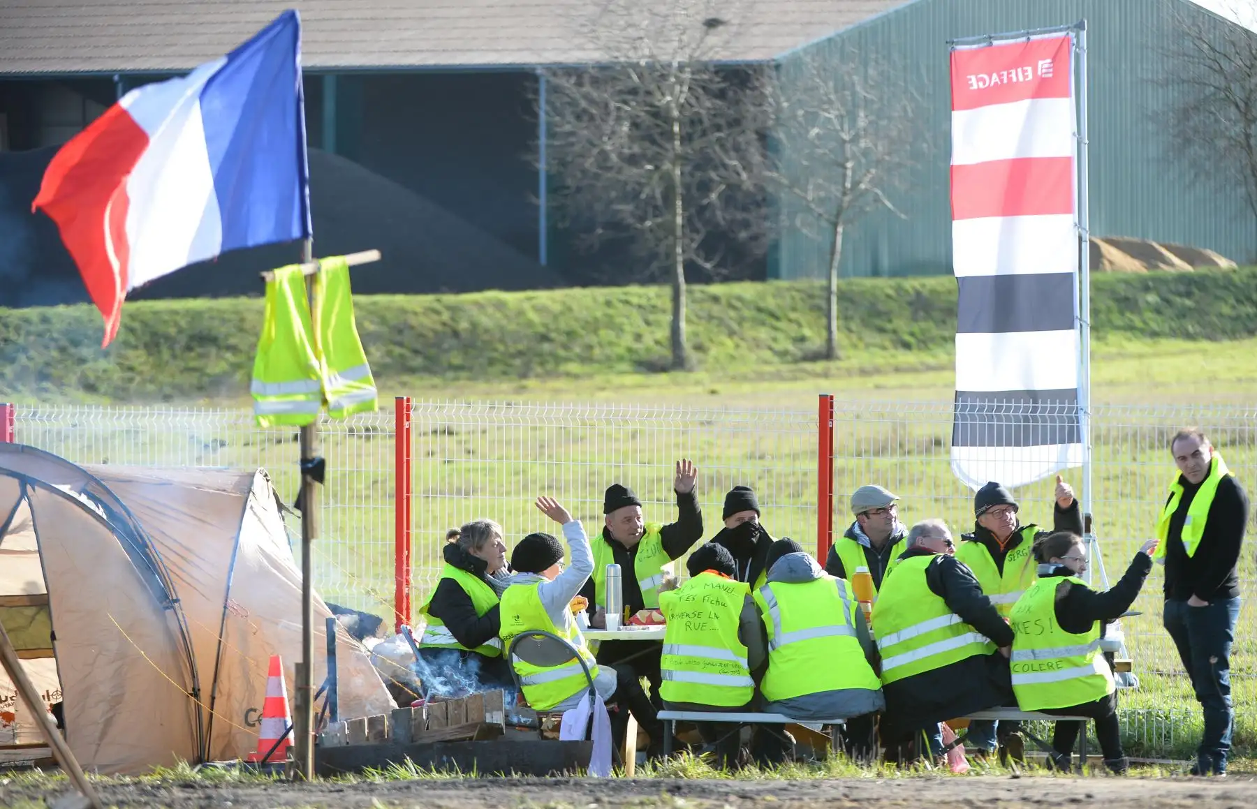 Los manifestantes de chalecos amarillos saludan a los conductores mientras comen a lo largo de una carretera que conduce a la circunvalación de Le Mans. AFP