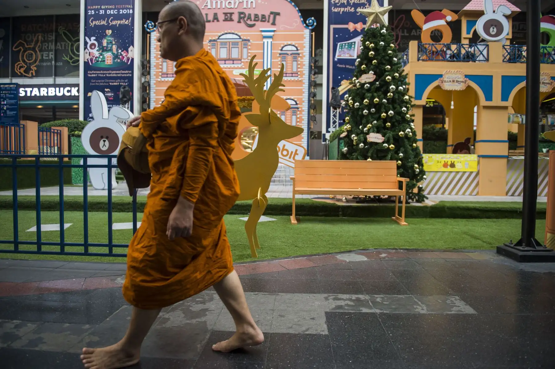 Un monje budista tailandés pasa las decoraciones navideñas en Bangkok. AFP