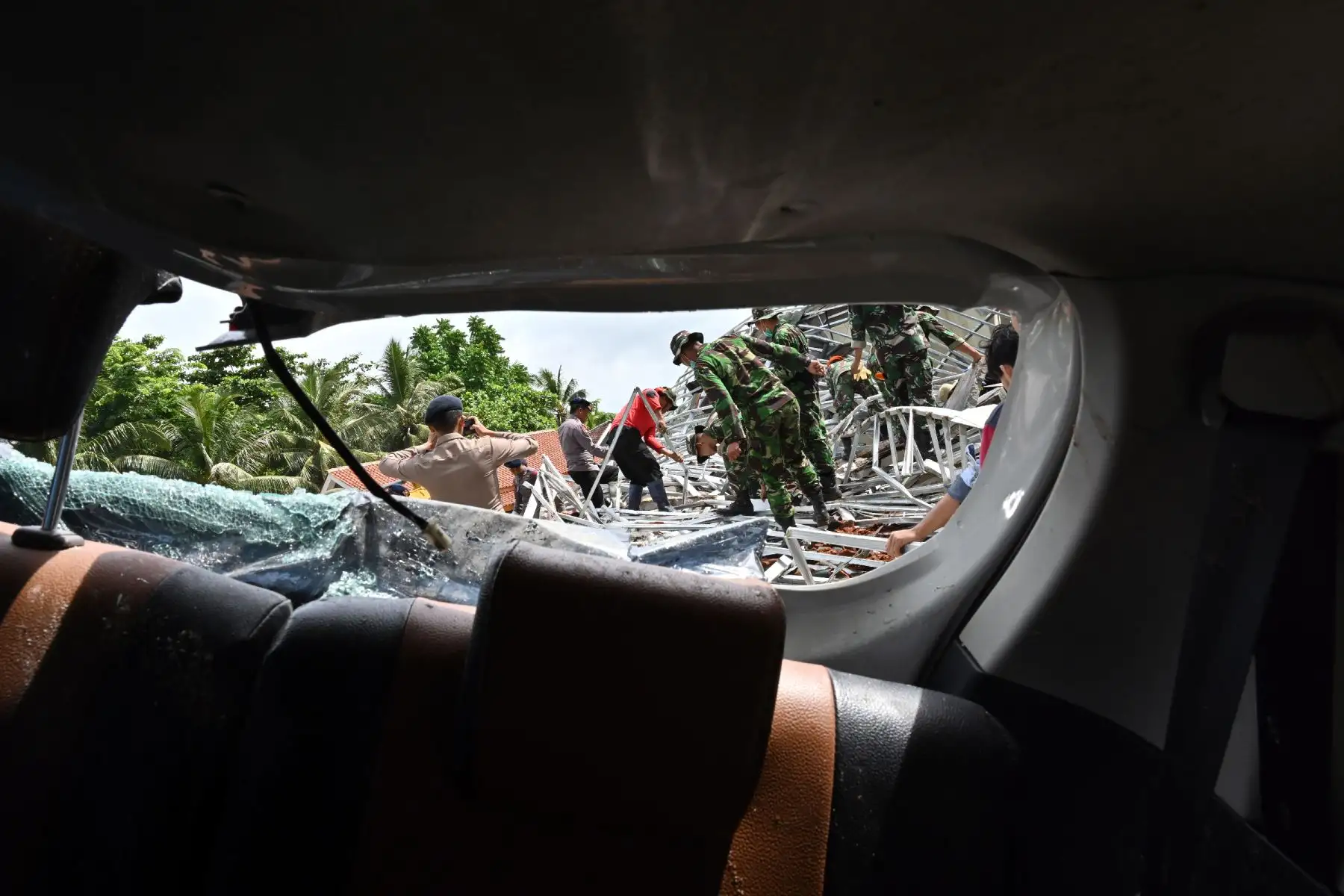 Miembros de un equipo indonesio de búsqueda y rescate son fotografiados a través de la ventana de un automóvil dañado mientras buscan víctimas en el alojamiento de Villa Stephanie en Carita, en la provincia de Banten. AFP