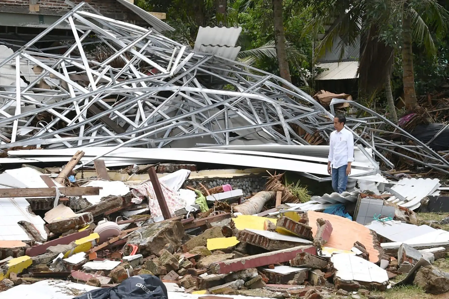 Presidente de Indonesia, Joko Widodo, caminando entre los escombros en Carita, provincia de Banten, dos días después de un tsunami, causado por la actividad en un volcán conocido como el "niño" de Krakatoa.  AFP