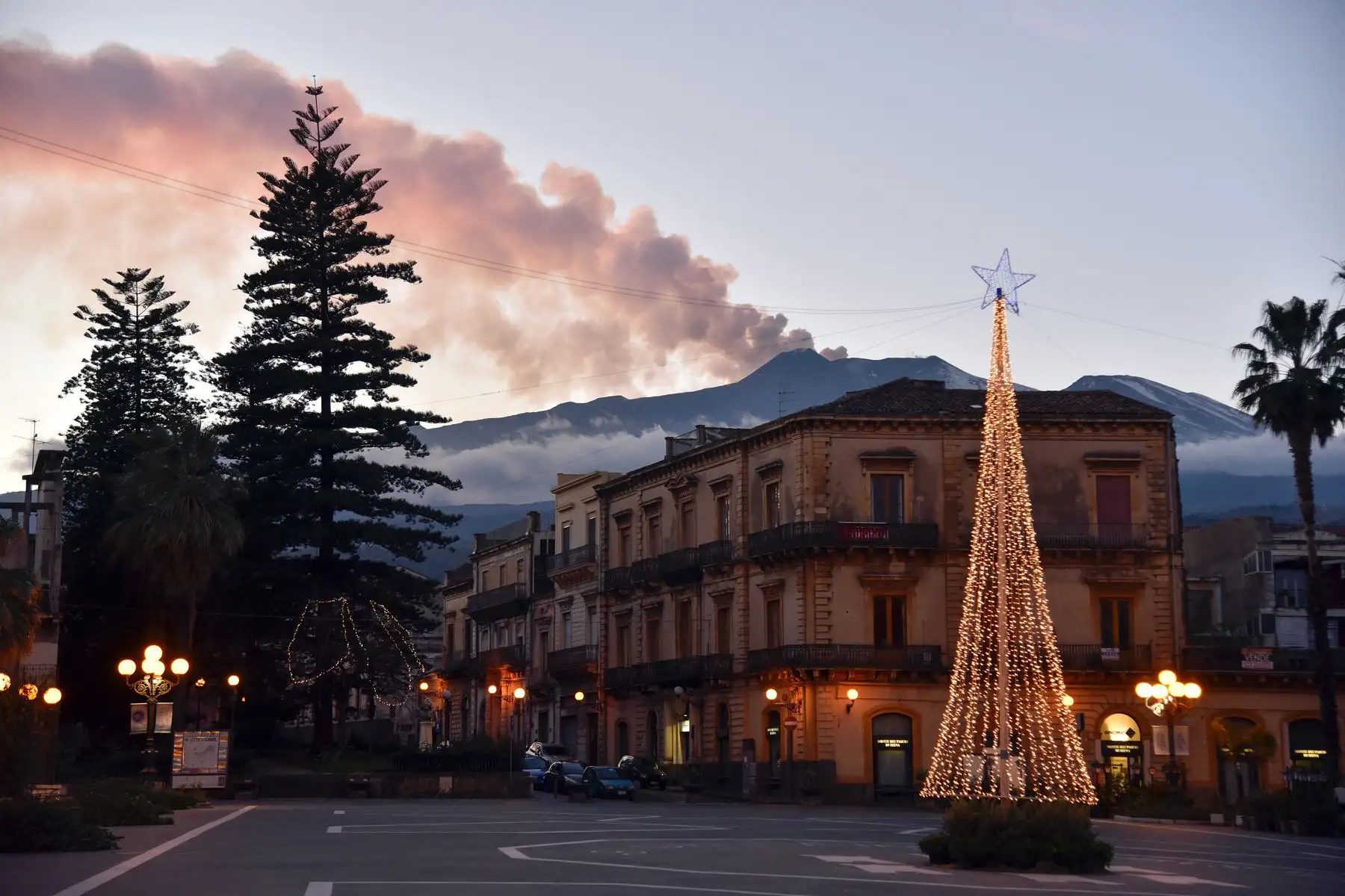 El humo se eleva desde el Monte Etna (Detrás R) sobre la ciudad de Giarre, Catania.  Se produjo un terremoto de magnitud 4.8. AFP