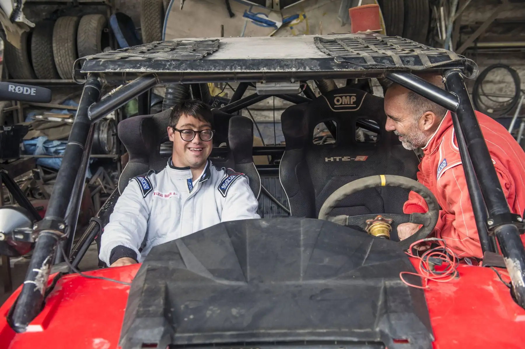 Jacques Barron (R) sonríe al lado de su hijo y copiloto Lucas Barron, de 25 años, en un taller de mecánica donde se está preparando su automóvil para participar en el próximo Rally Dakar. Foto: AFP