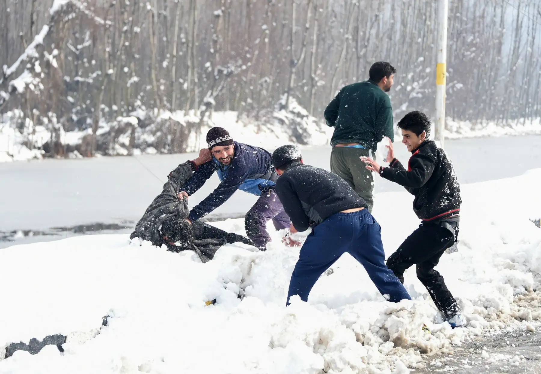 Los jóvenes de Cachemira juegan con nieve en las orillas del lago Dal después de la nevada en Srinagar.  AFP
