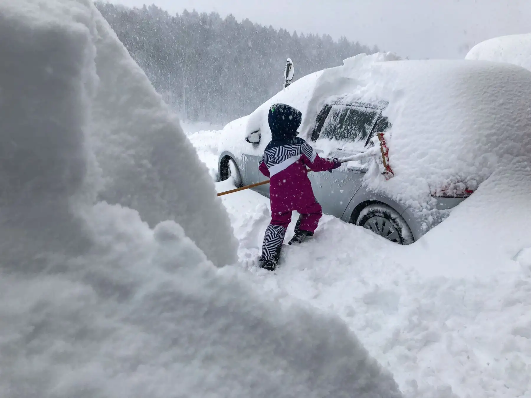 Un niño limpia una ventanilla de nieve de un automóvil en Salzburgo, Austria, mientras cae nueva nieve. AFP