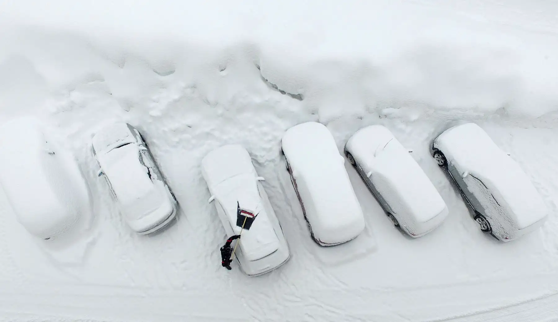 Una fotografía aérea muestra a un hombre limpiando su automóvil de la nieve después de fuertes nevadas en Ramsau am Dachstein, Austria. AFP