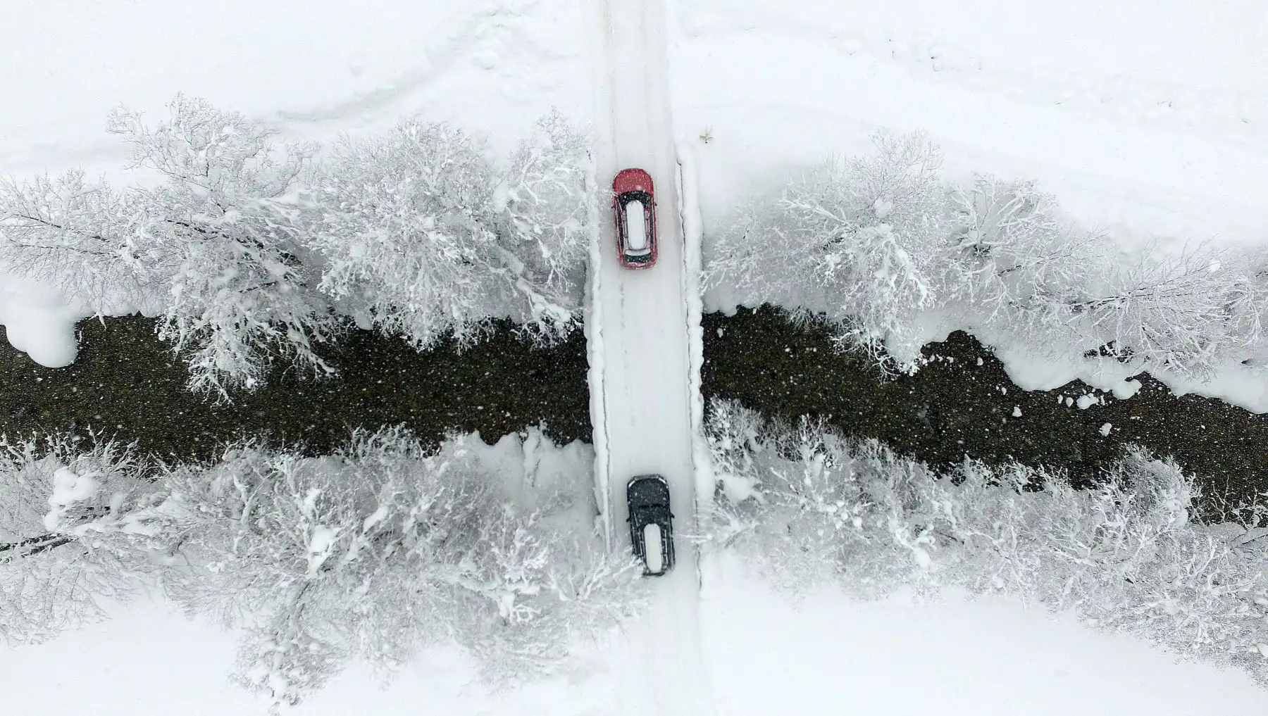 En Untertauern, Austria, muestra una vista aérea de autos que cruzan un puente mientras la calle está cubierta de nieve. AFP