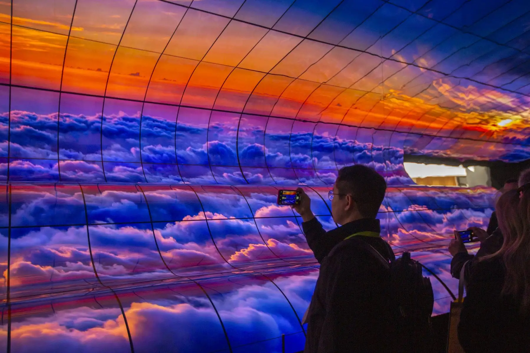 La gente toma fotos de teléfonos inteligentes de un gran panel de televisores LG OLED curvos en la exhibición de LG durante el CES 2019 en Las Vegas. AFP